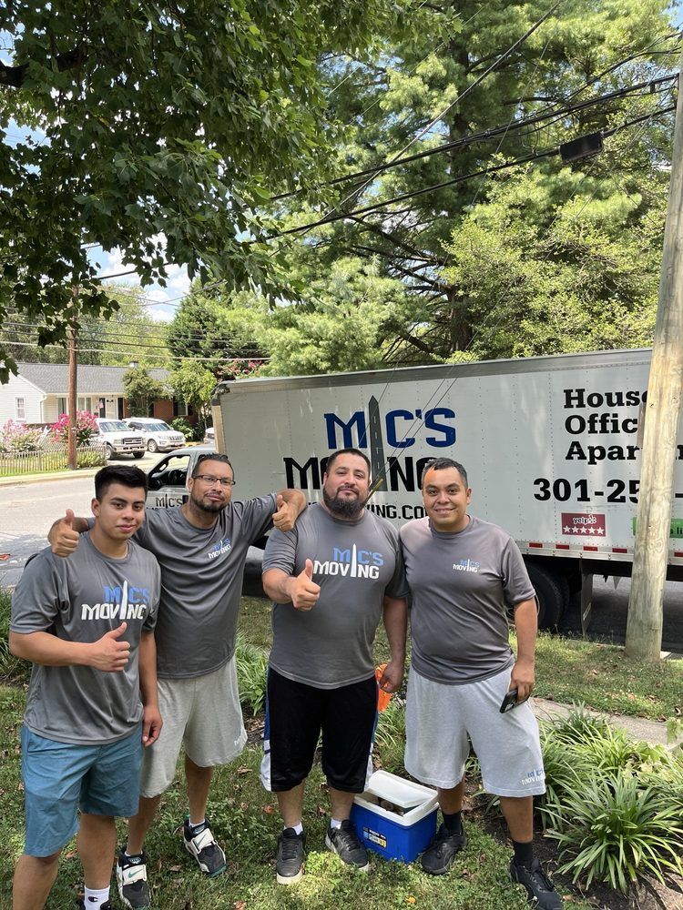 A man is pushing a cardboard box down a street.