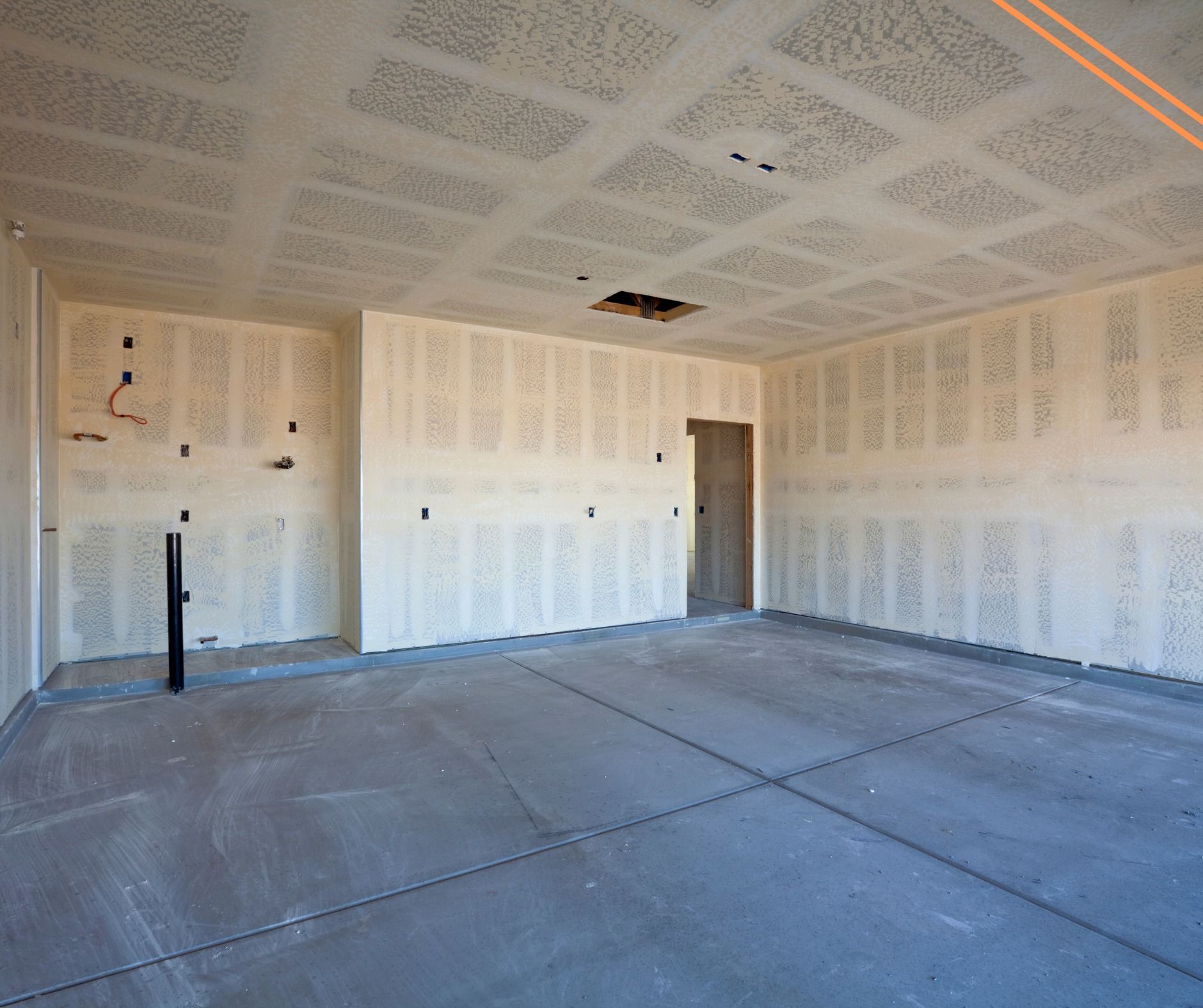 Interior of a room under construction with drywall on walls and ceiling, concrete floor, and an open doorway.