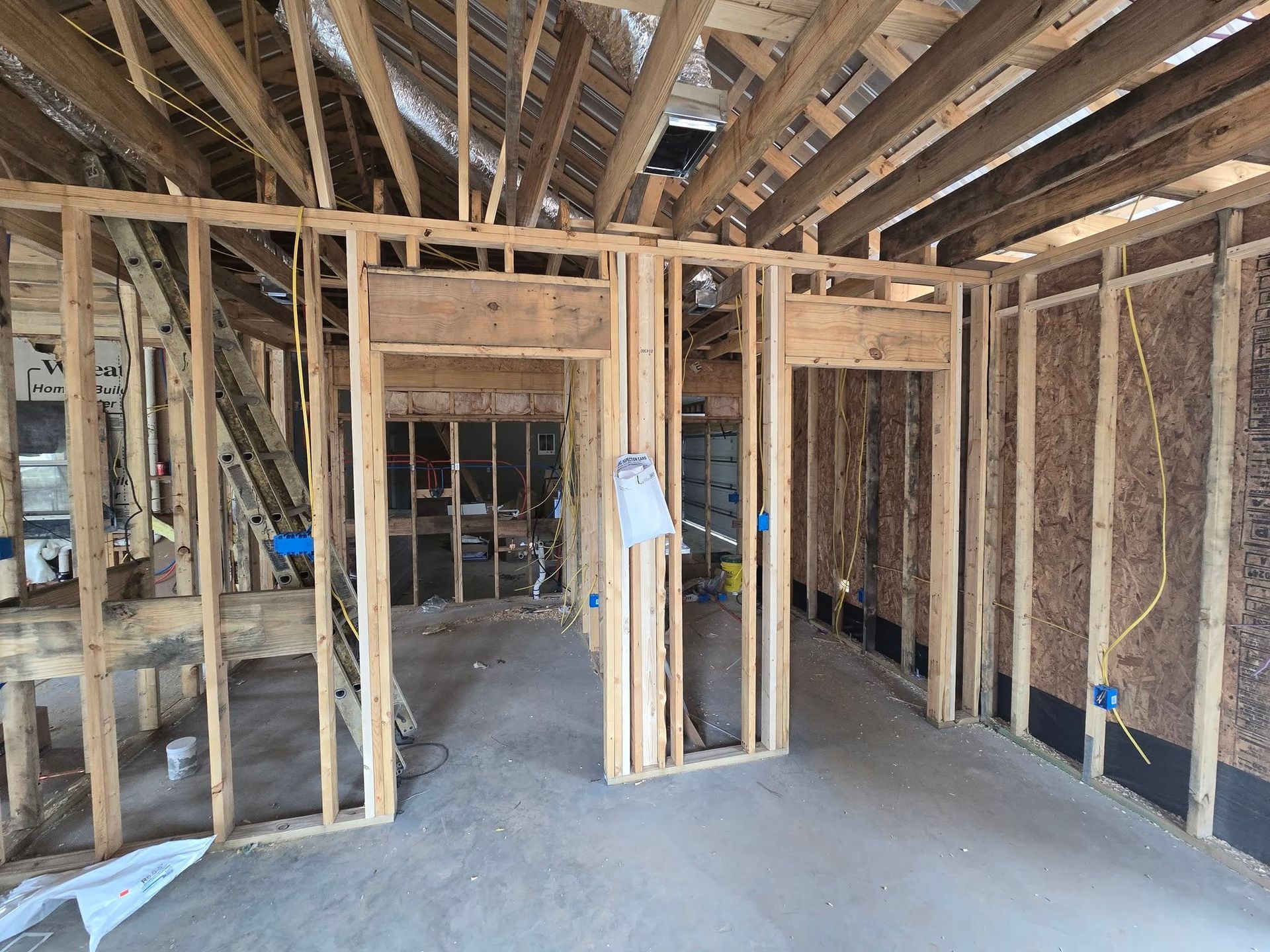 Interior of a building under construction, wooden frame walls with doorways. Electrical wiring is visible.
