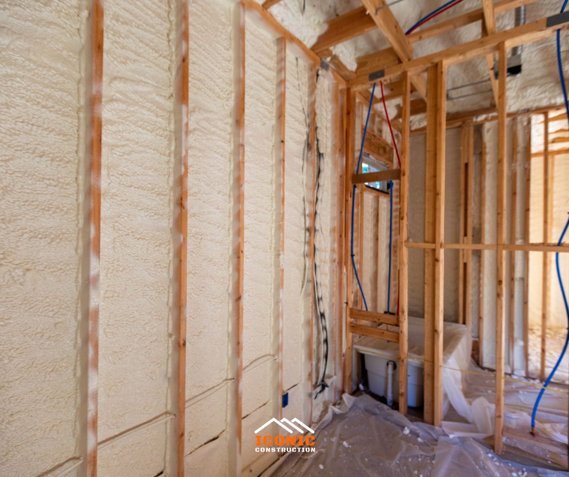 Interior framing with spray foam insulation filling the wall cavities; plumbing lines are visible.