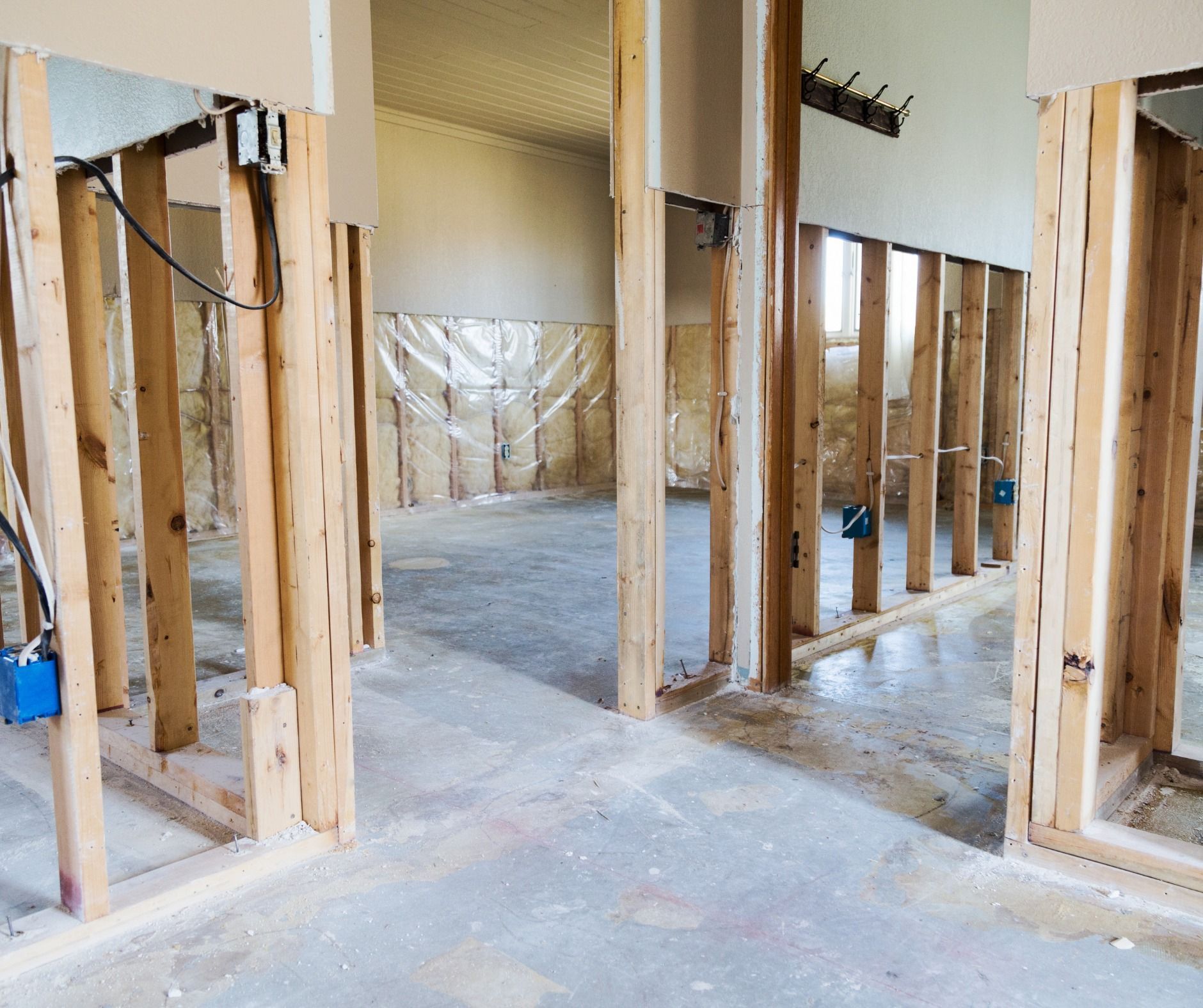 Interior view of a room under construction with exposed wooden framing. Walls are partially built, concrete floor.