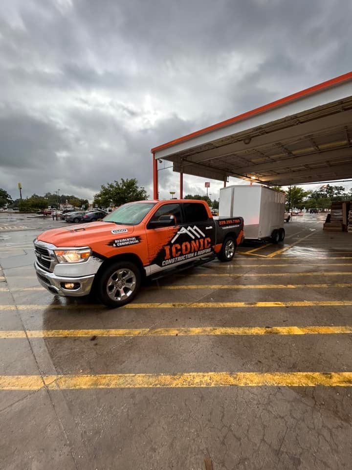 Orange and white truck with a trailer parked under a canopy; the truck has 