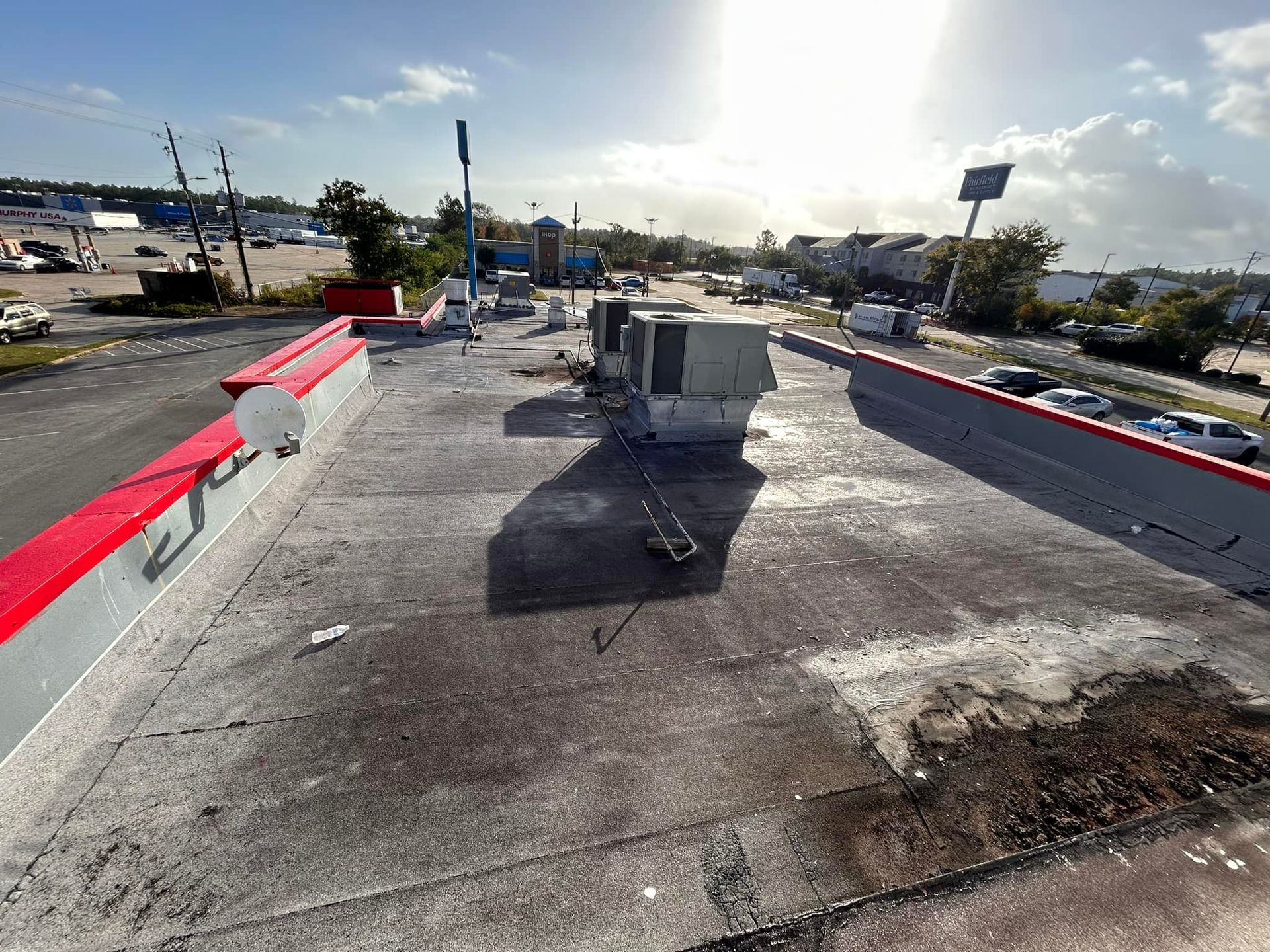 Rooftop view of a building with HVAC units, antennas, and weathered concrete. Sunlight shines on the scene.