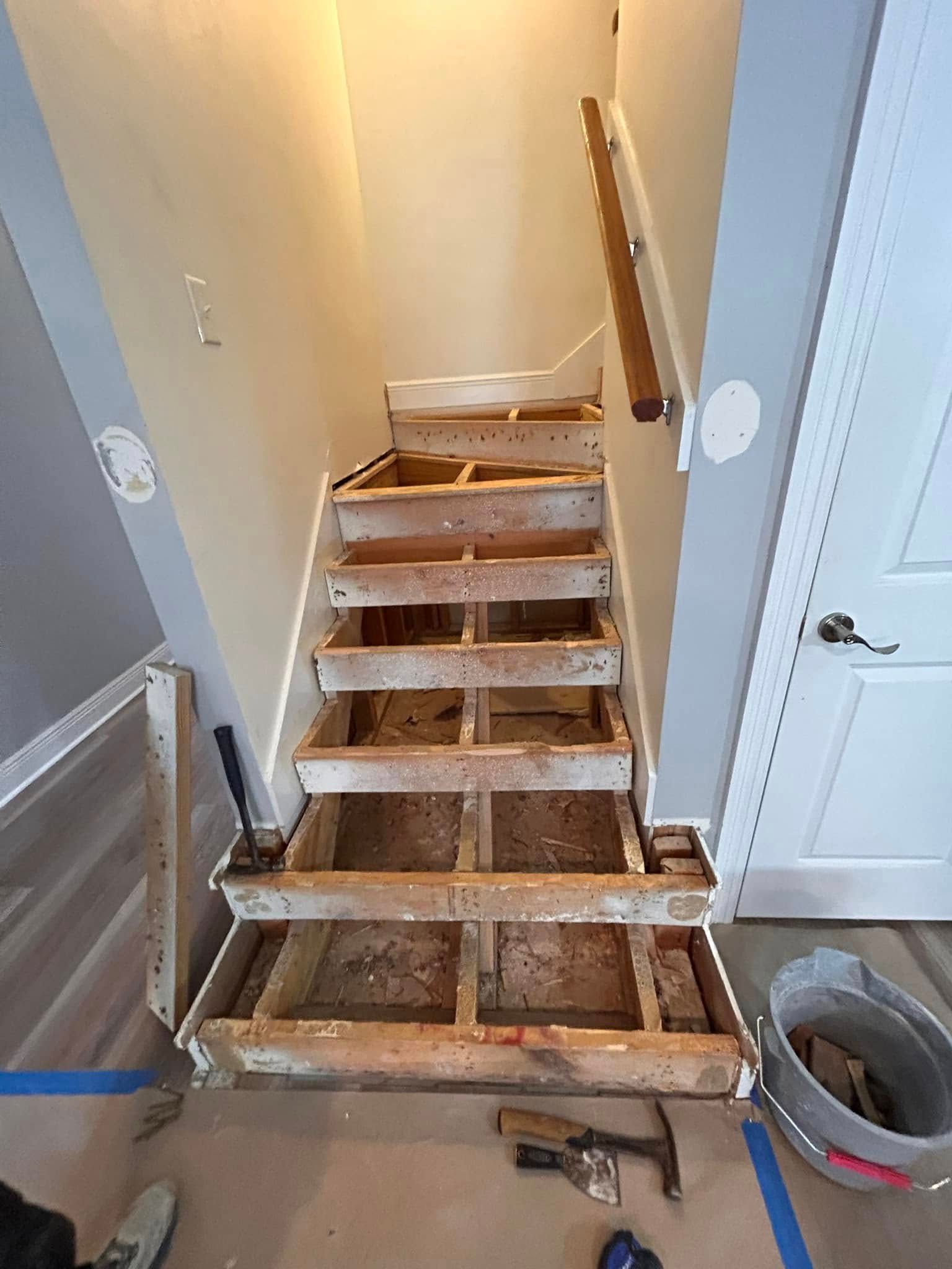 A staircase under renovation.  Treads and risers are removed, showing the skeletal frame.  Handrail present.