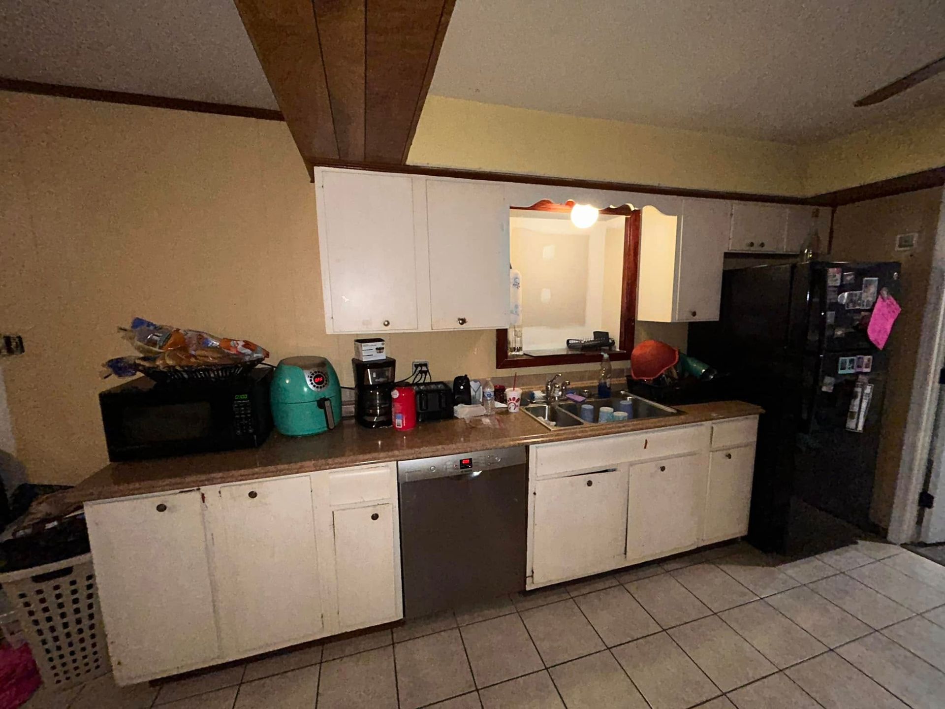 Kitchen with white cabinets, a black refrigerator, and appliances on the counter, including a microwave and air fryer.