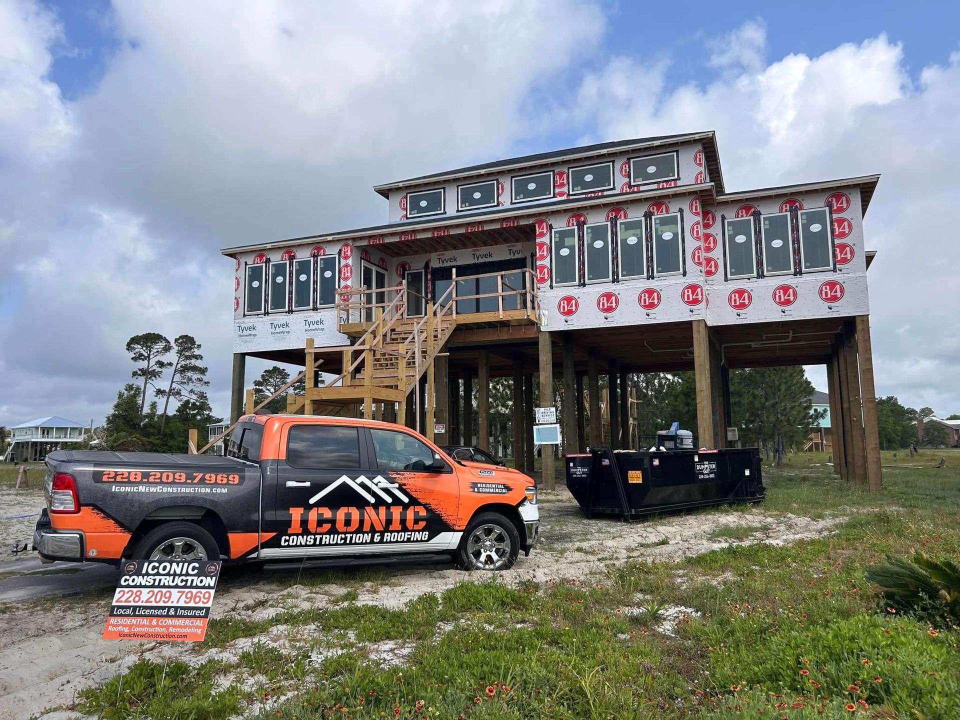 A two-story beach house under construction, with a truck labeled 