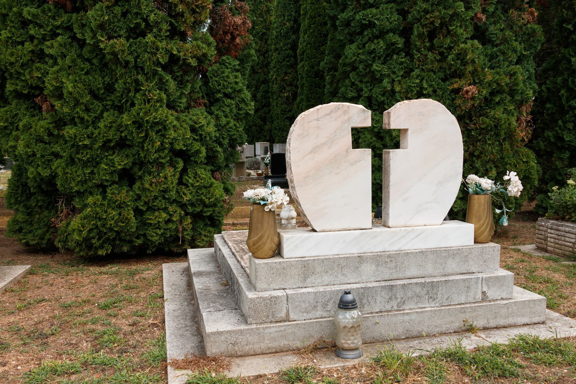 A grave with a heart and a cross on it in a cemetery.