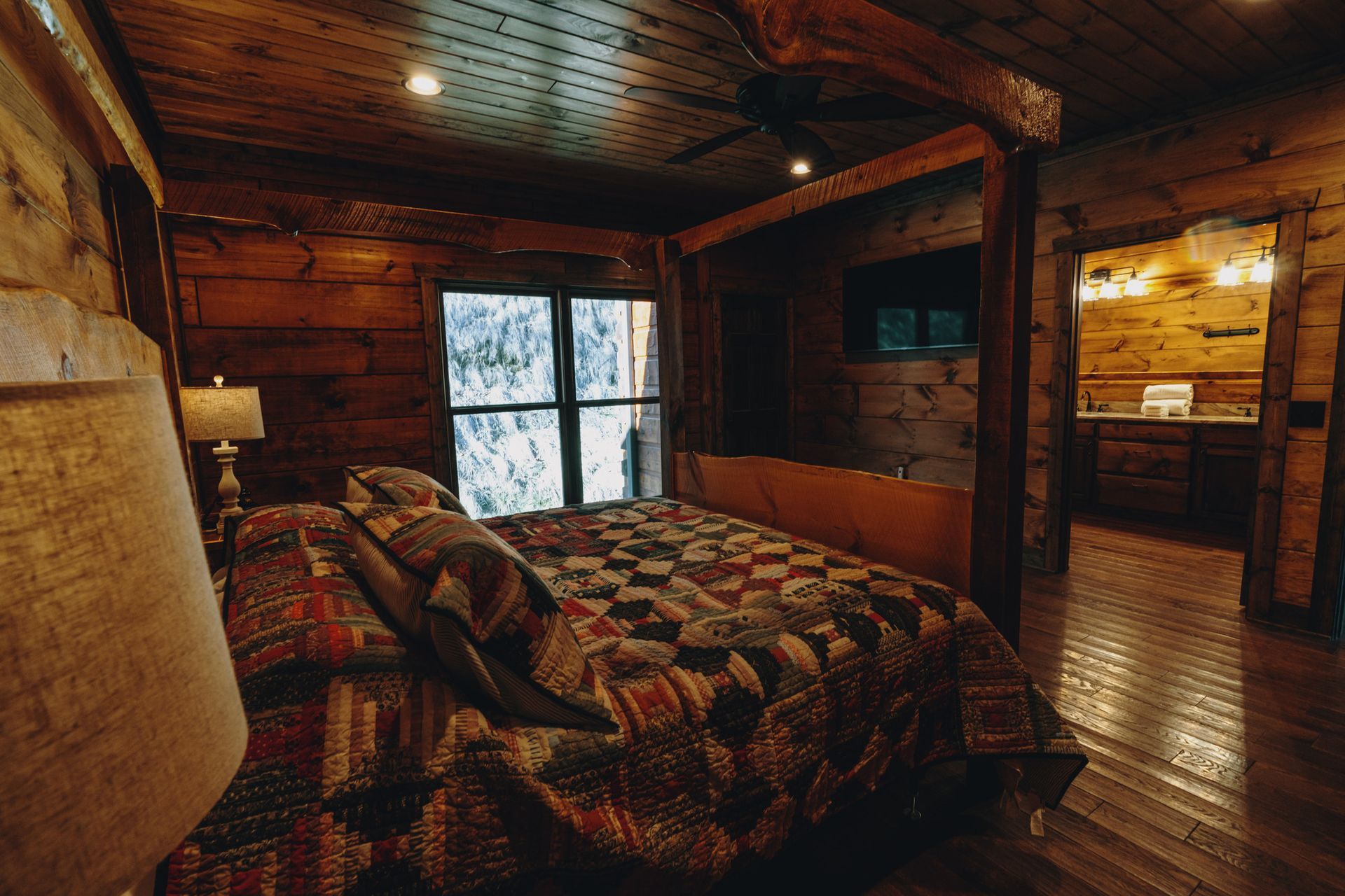 a bedroom in a log cabin with a king size bed and a large window .
