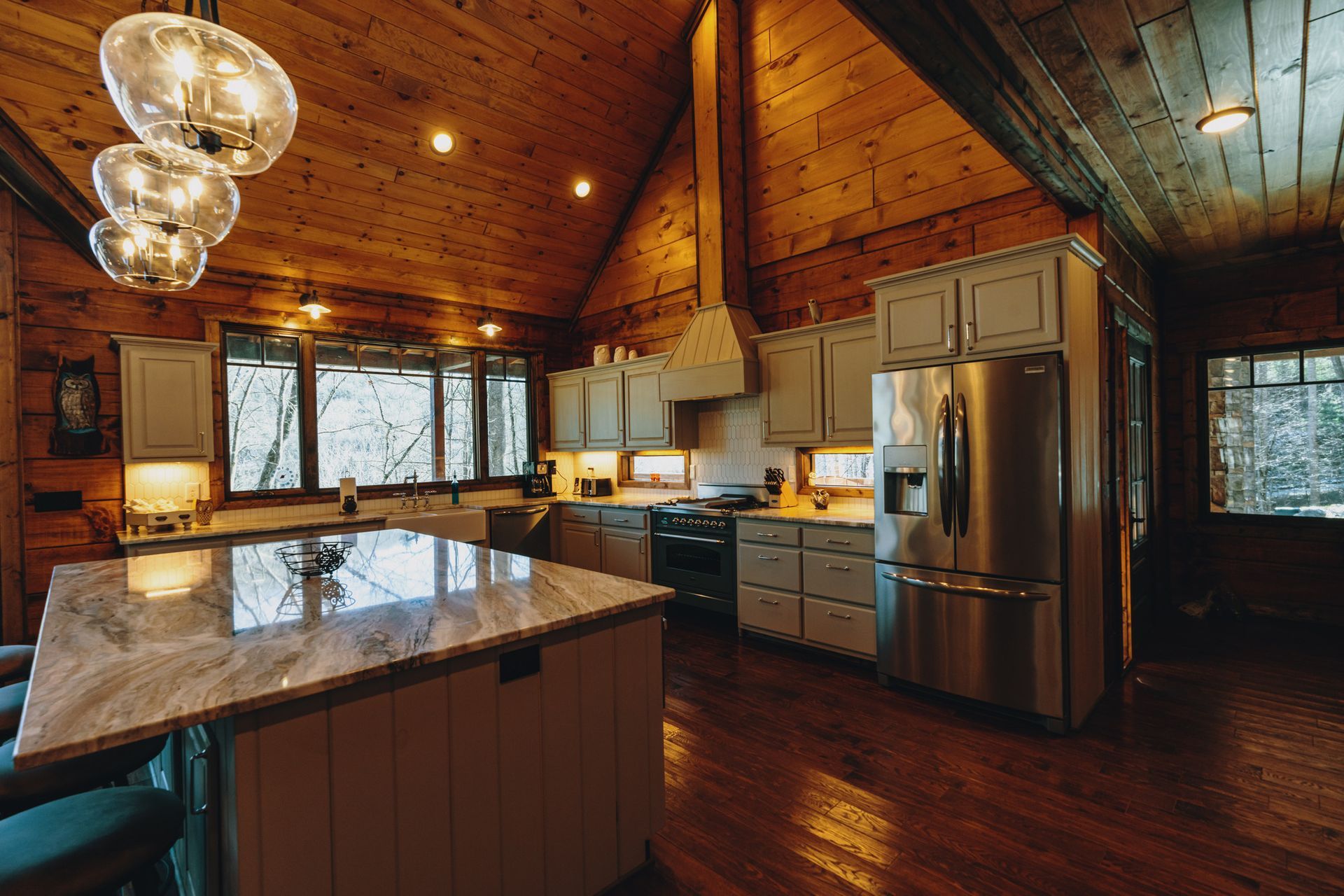a kitchen in a log cabin with stainless steel appliances and marble counter tops .
