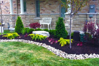 A stone walkway leading to a house in a lush green yard.