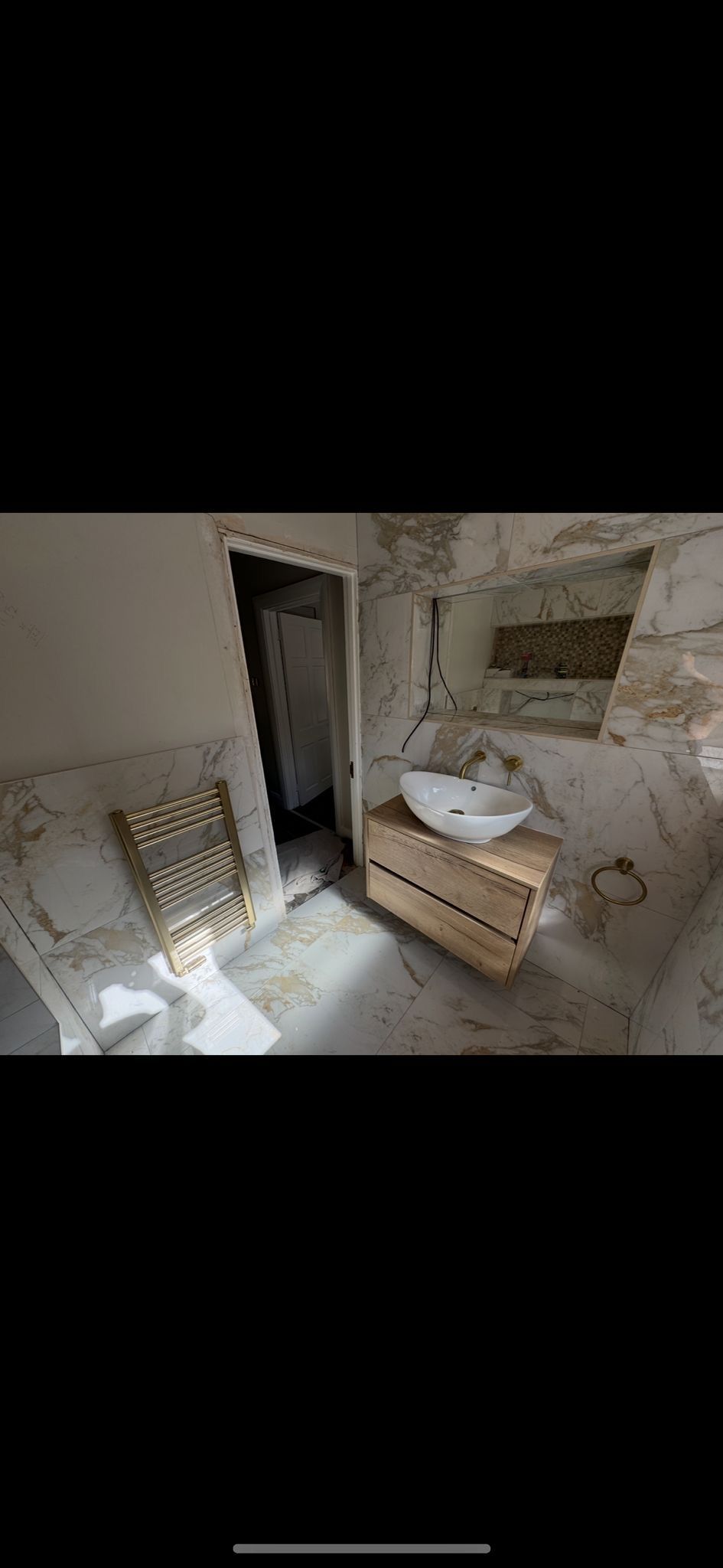 Rustic bathroom vanity with round mirror, woven baskets, and a hanging light over a stone sink.
