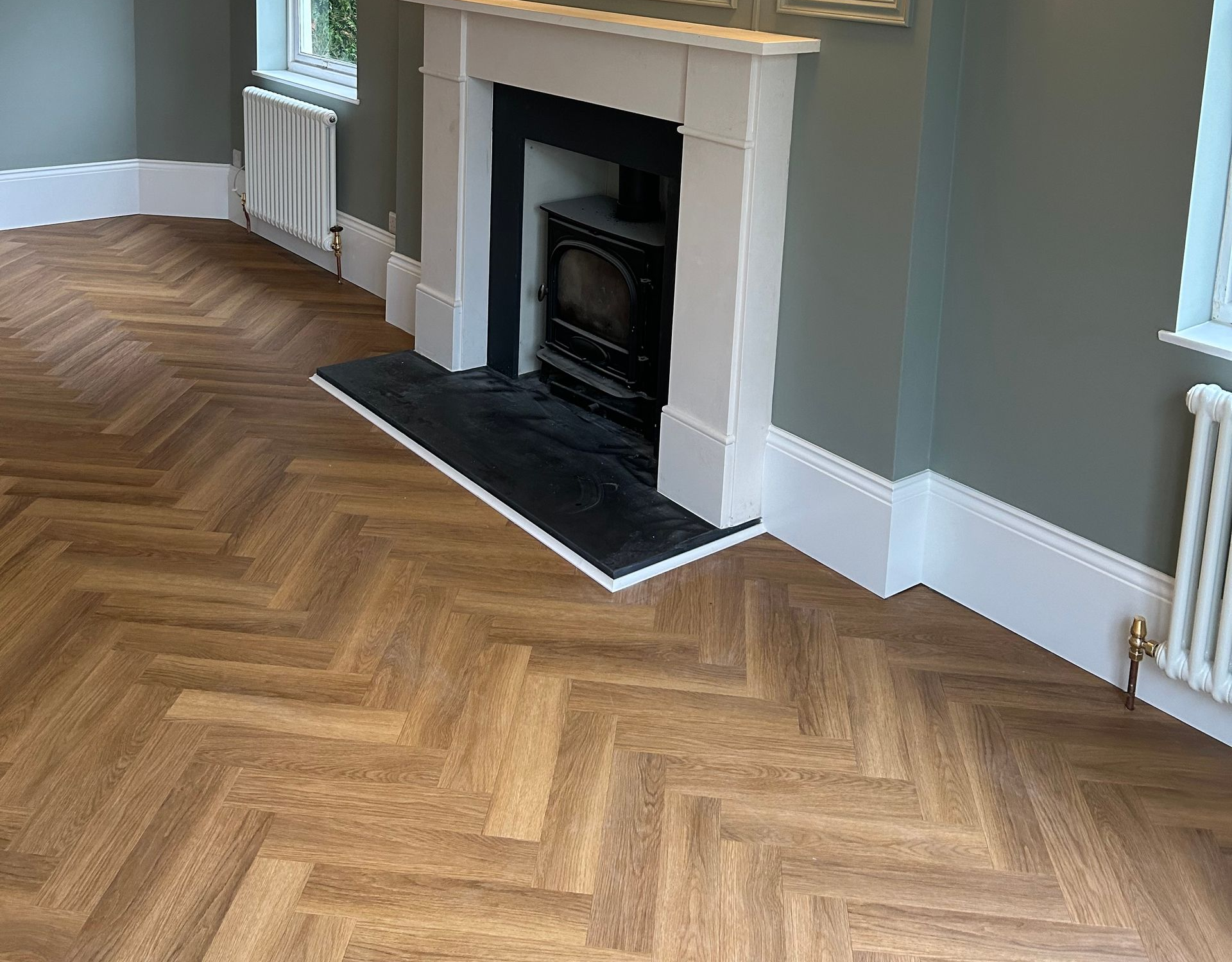 Elegant gray living room with herringbone wood floor, white fireplace, and wall sconces