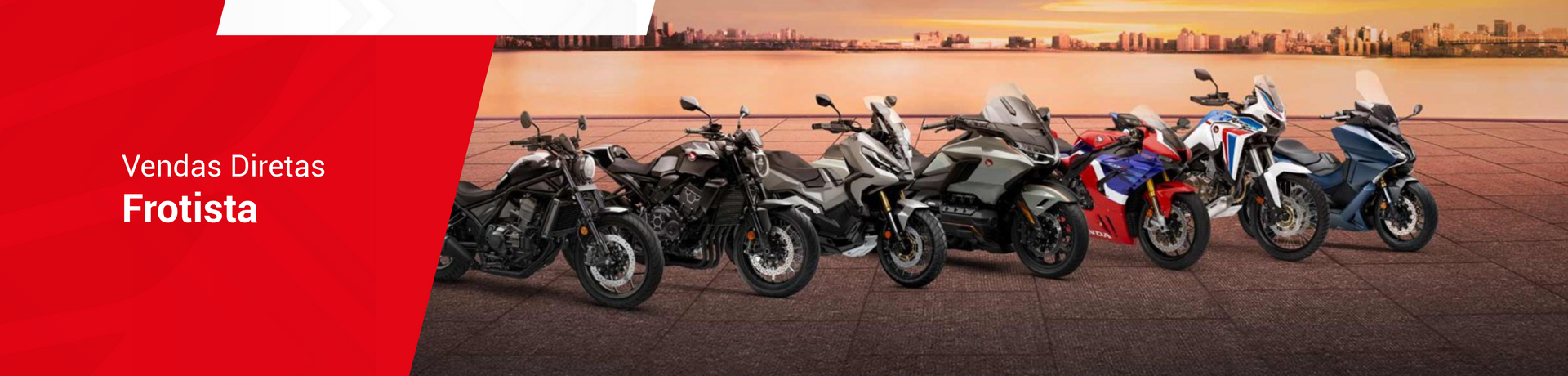 Motocicletas expostas em uma superfície marrom e arenosa com fundo laranja e uma faixa lateral vermelha.