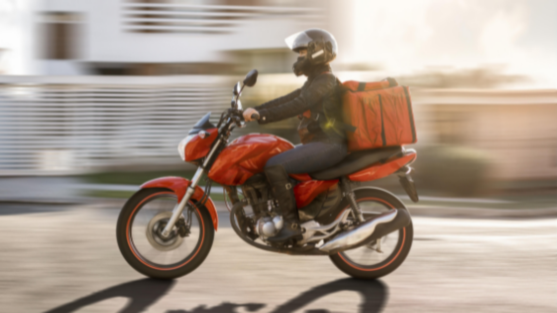 Entregador em motocicleta vermelha com bolsa térmica para alimentos, dirigindo em alta velocidade.