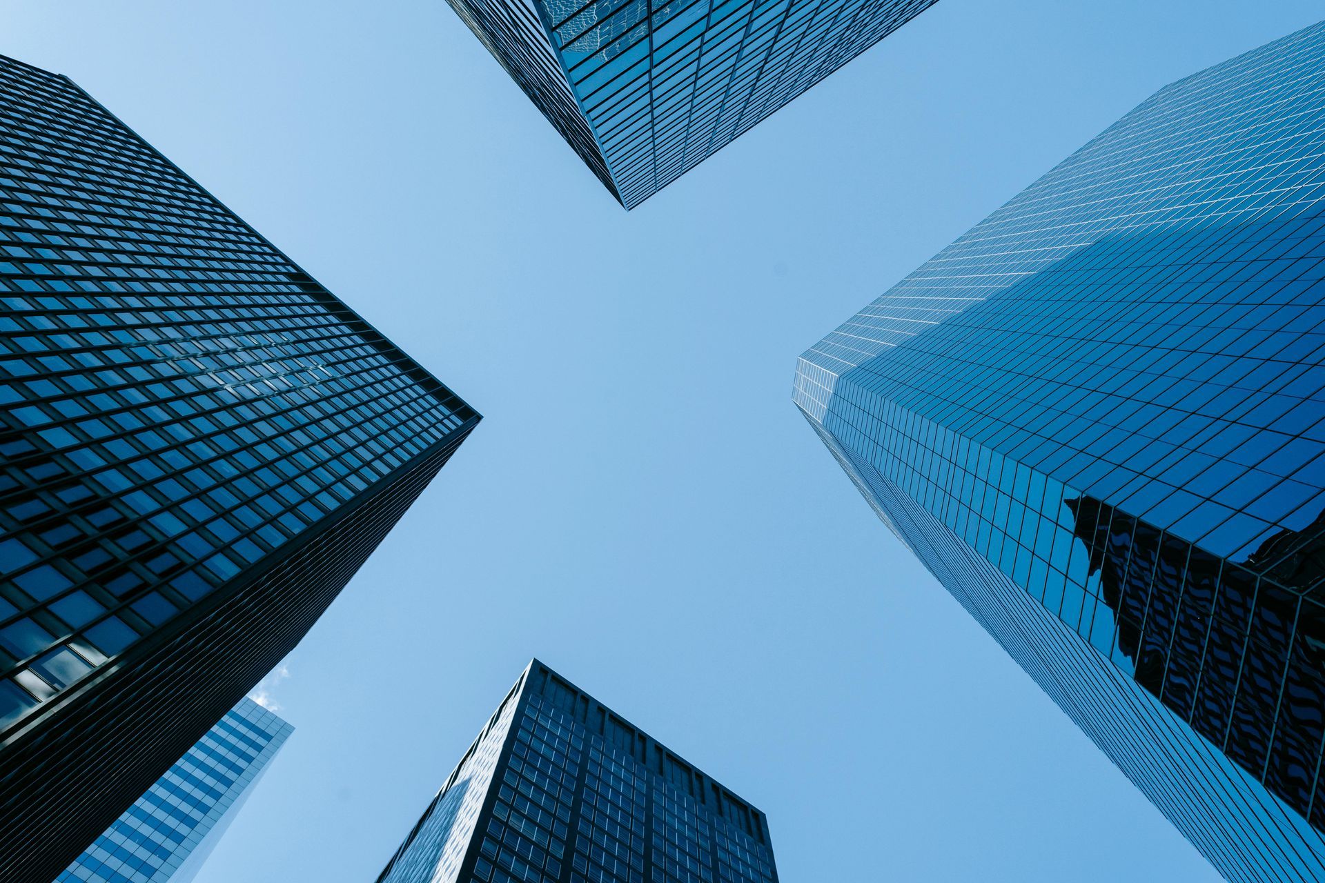 Low-angle view of four tall skyscrapers against a clear, blue sky.