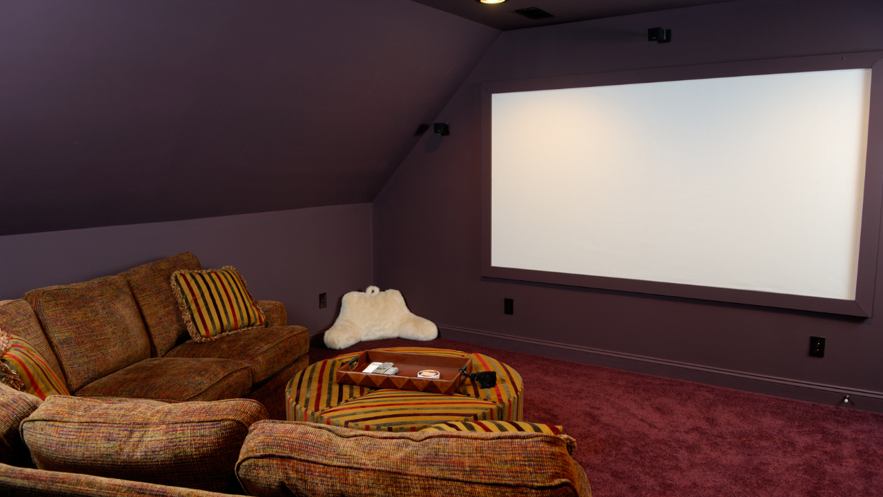 Home theater room with purple walls, brown sofa, and white projection screen.