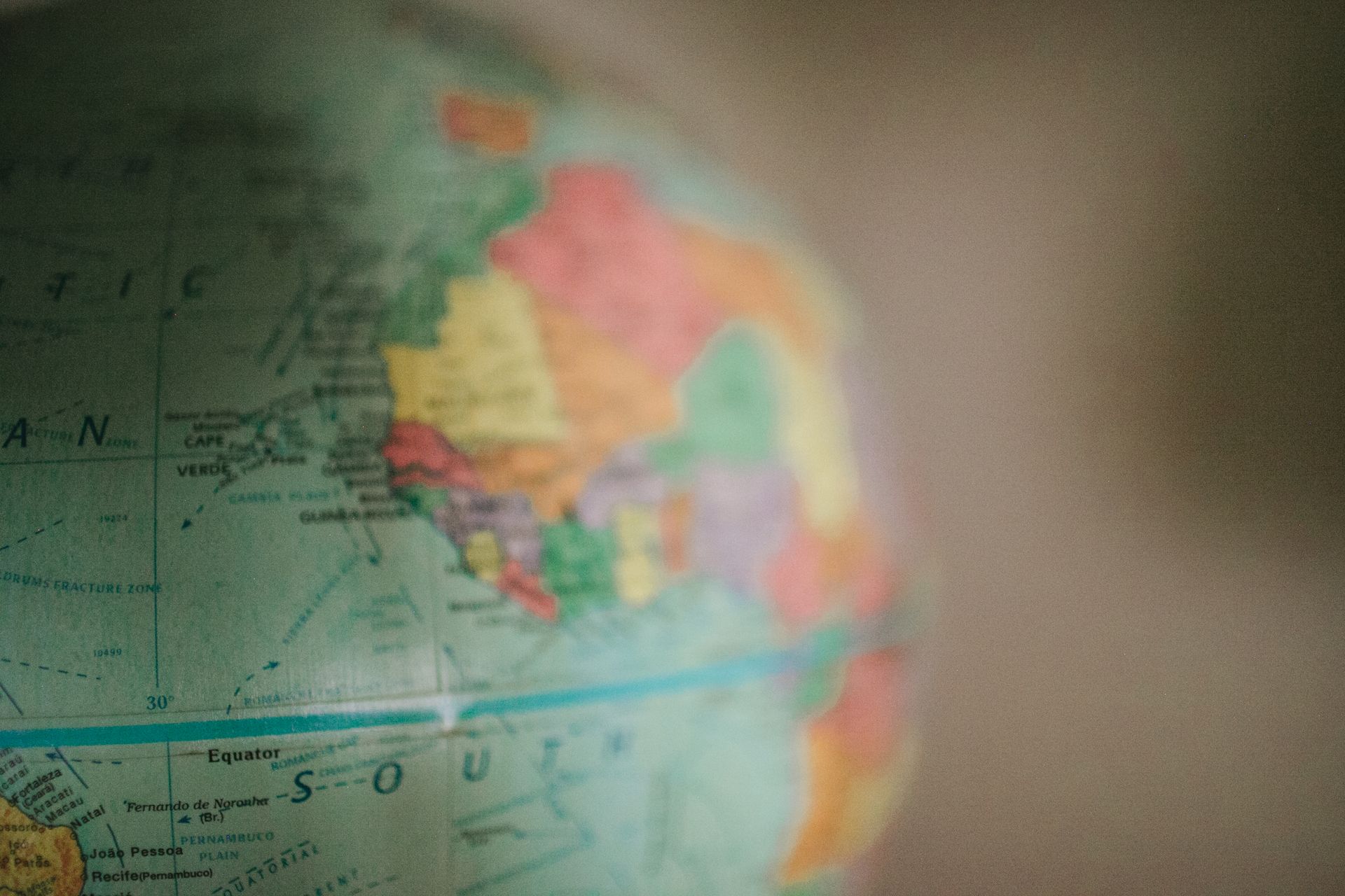 Blurred close-up of a colorful world map, with South America visible on the left.