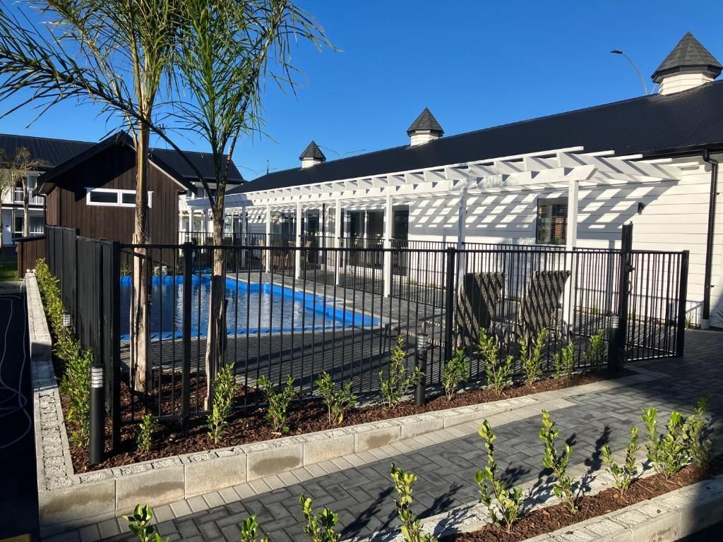 A fence surrounds a swimming pool in front of a house.