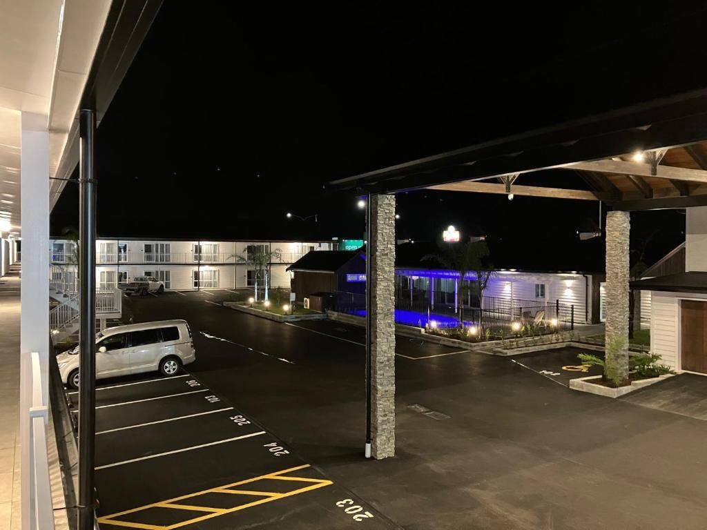 A car is parked in a parking lot in front of a hotel at night.