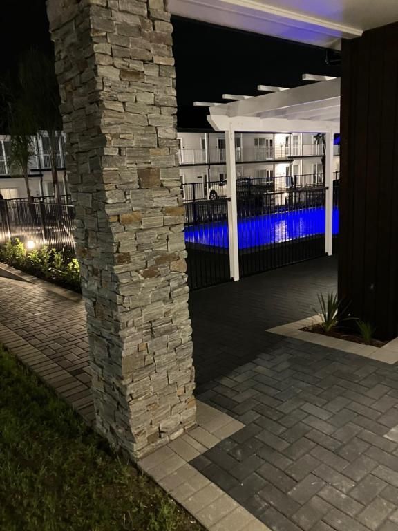 A brick walkway leading to a swimming pool at night