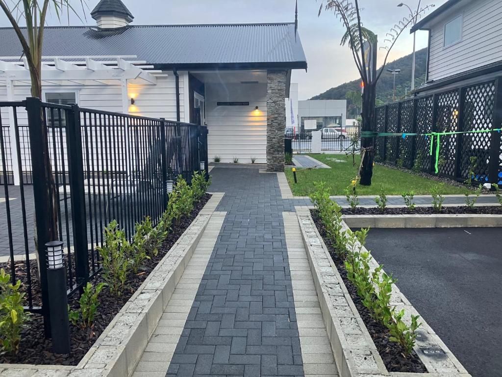 A brick walkway leading to a house with a fence.
