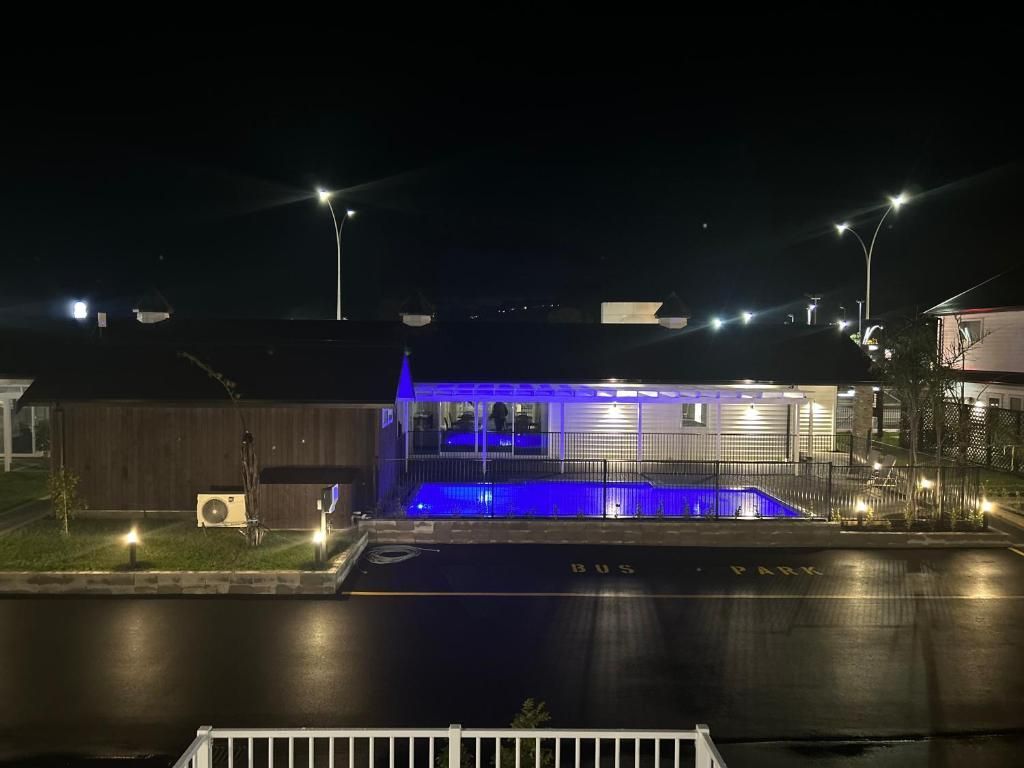 A large swimming pool is lit up at night in front of a house.