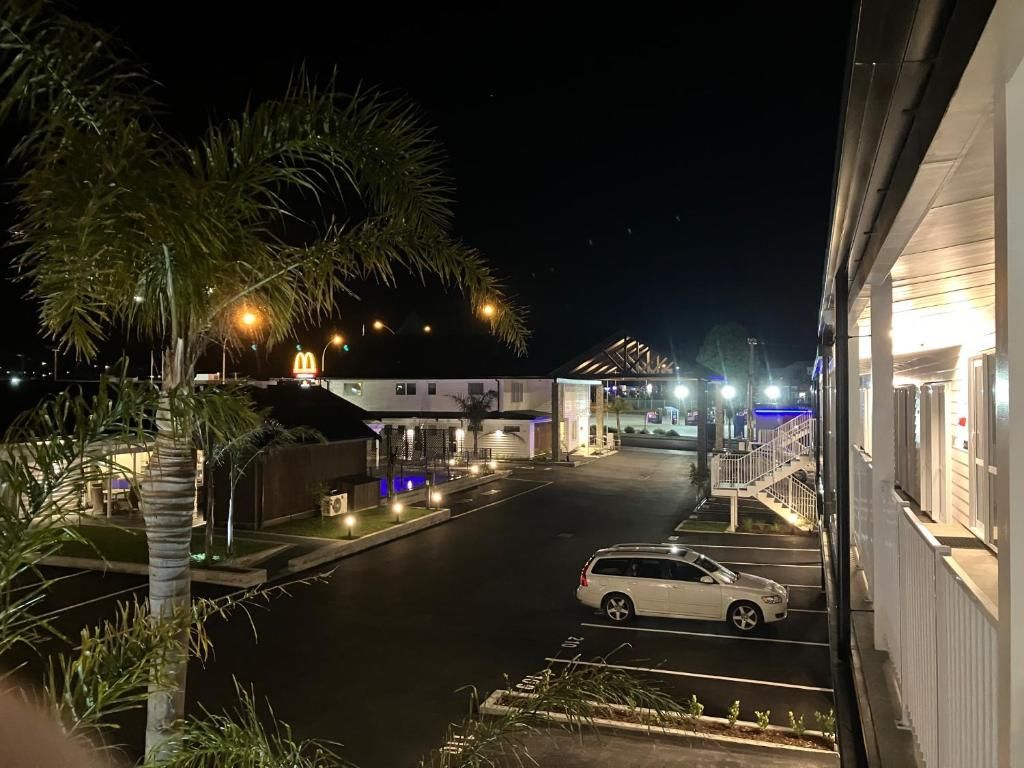 A white van is parked in a parking lot in front of a hotel at night.