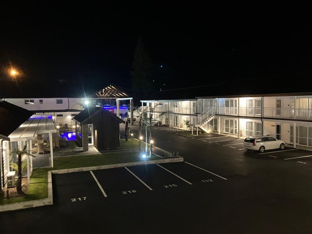 A motel with cars parked in front of it at night.