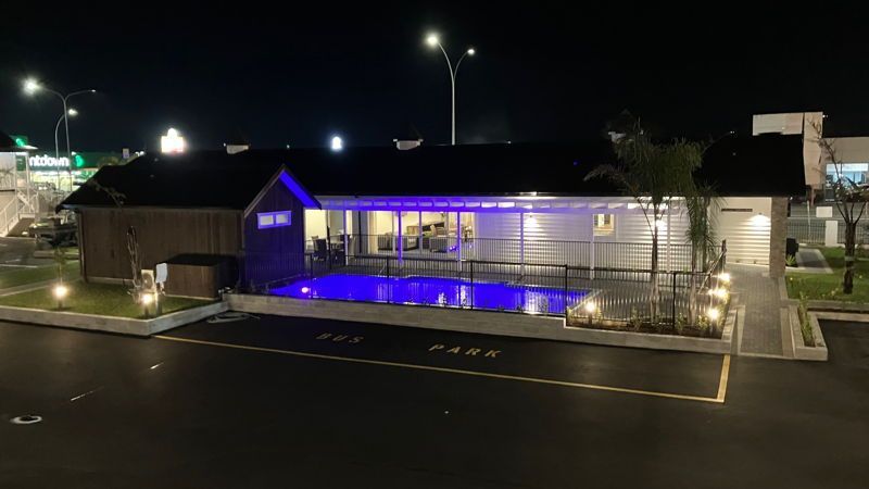 A house with a swimming pool in front of it at night.