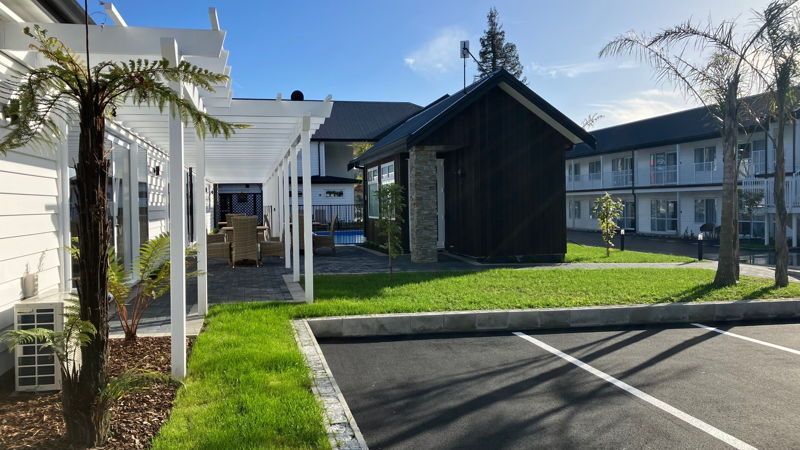 A row of houses with a pergola and a parking lot in front of them.
