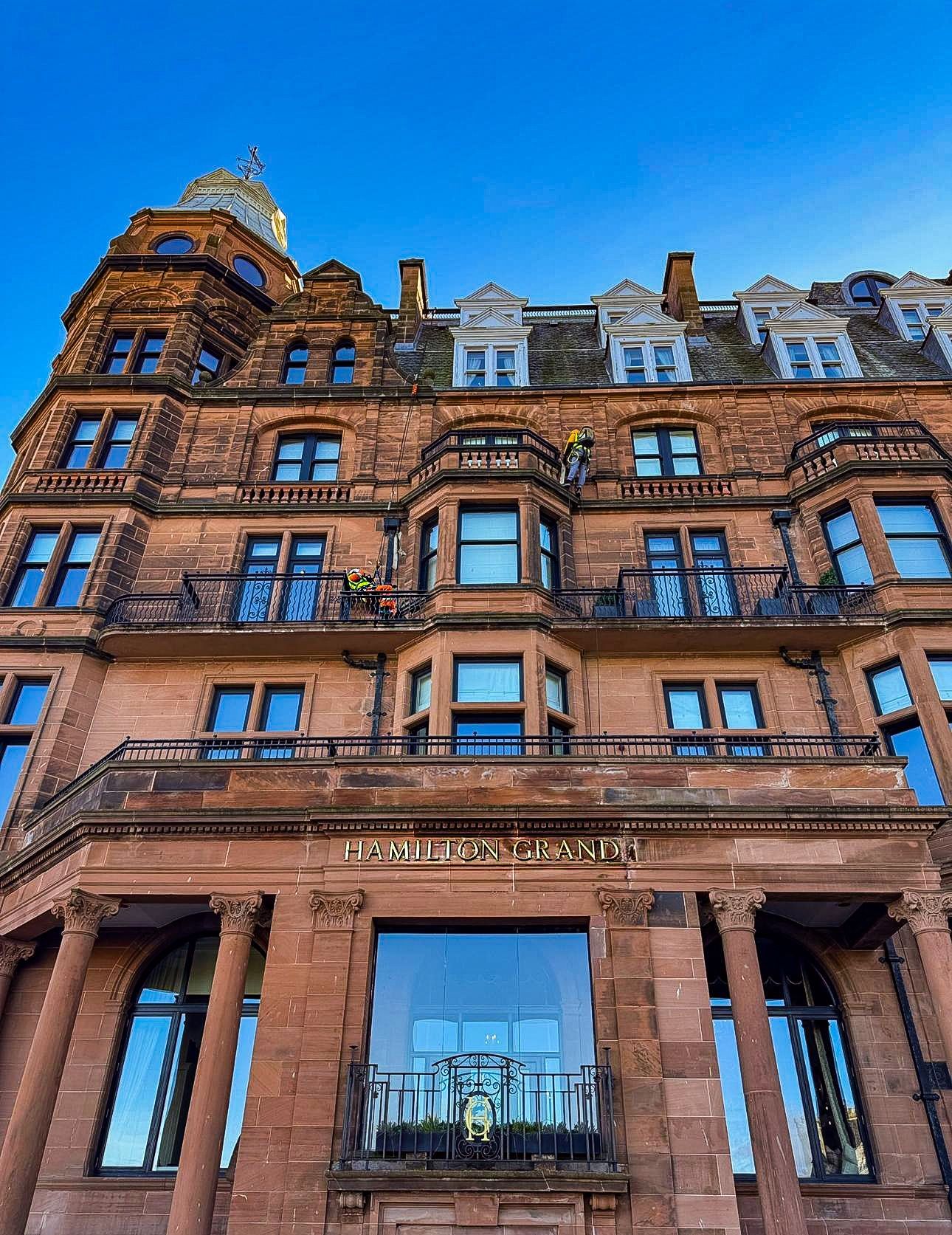 Low-angle shot of a tall, red sandstone historic building with ornate architectural details and arched windows.
