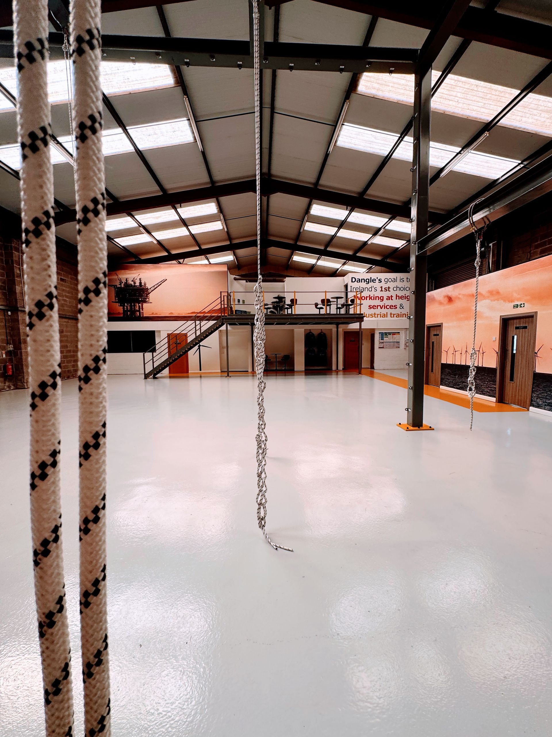 A large warehouse training centre with ropes hanging from the ceiling.