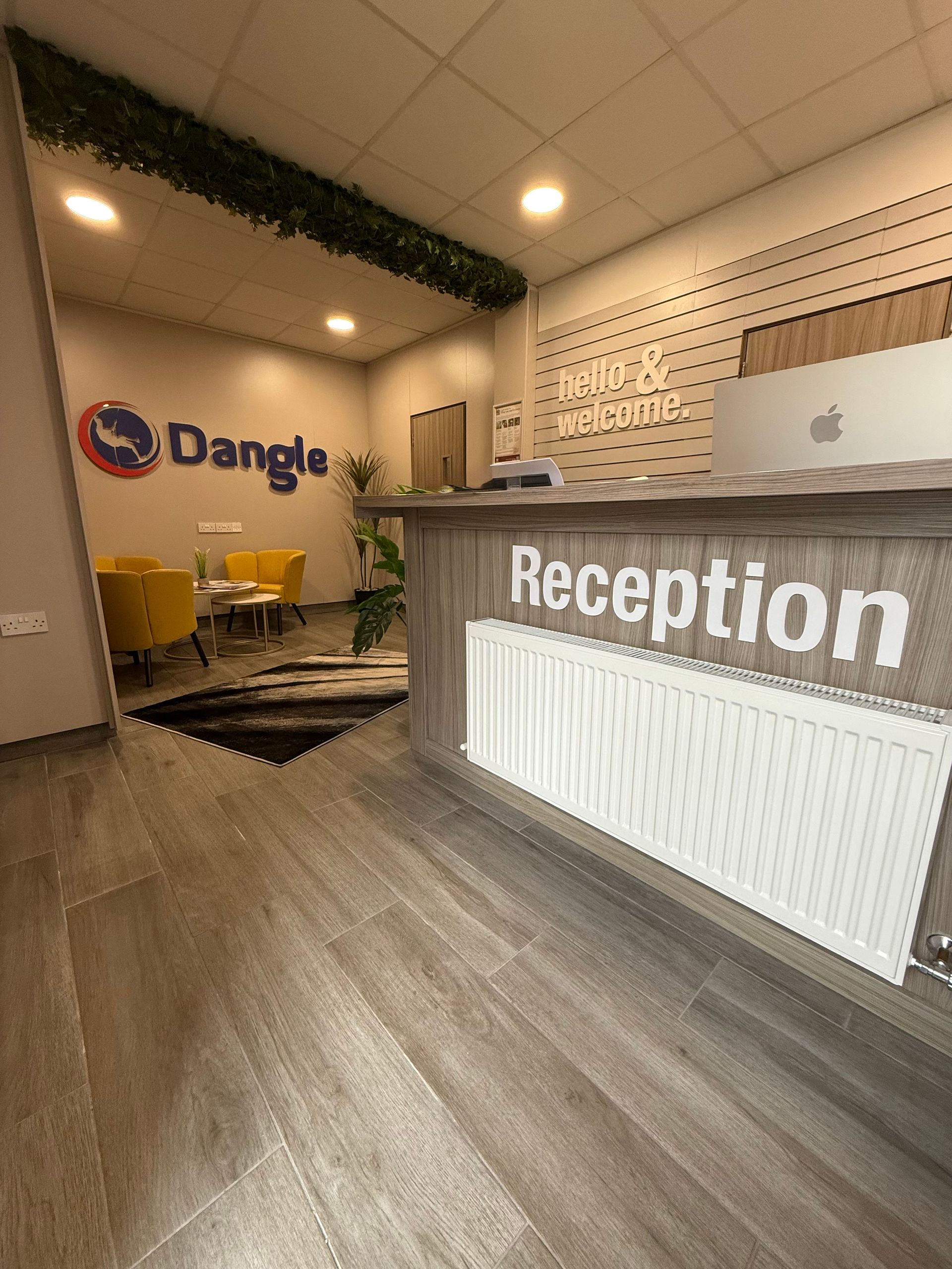 A reception desk with a white radiator in a room saying hello & welcome to Dangle Academy.