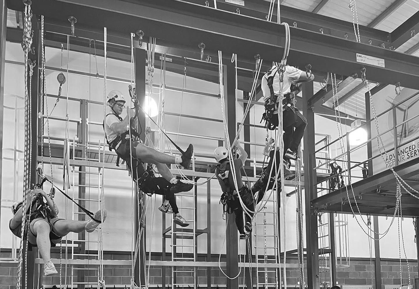 A black and white photo of a group of people climbing scaffolding.
