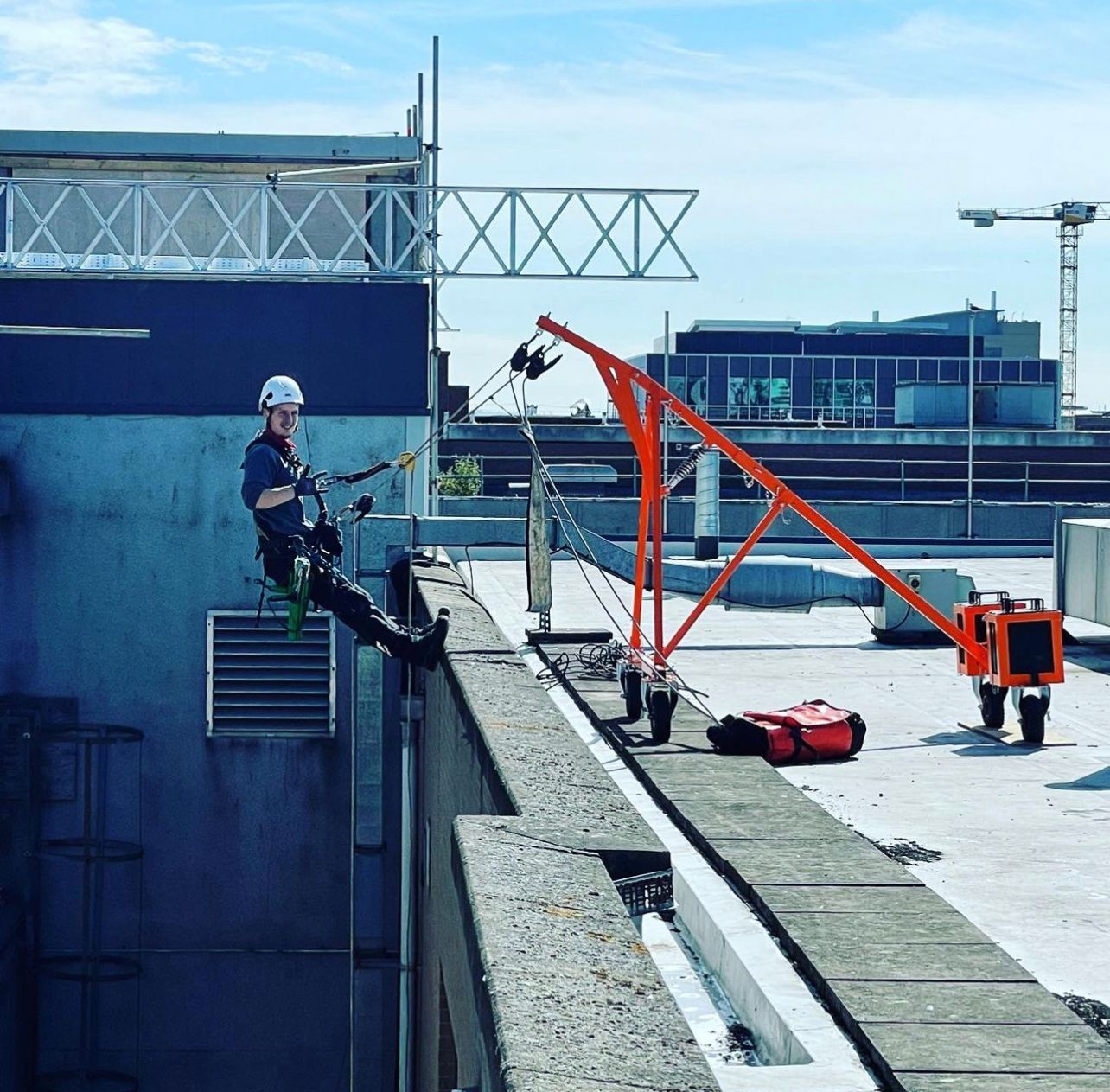 A man is sitting on the side of a building about to abseil down it.