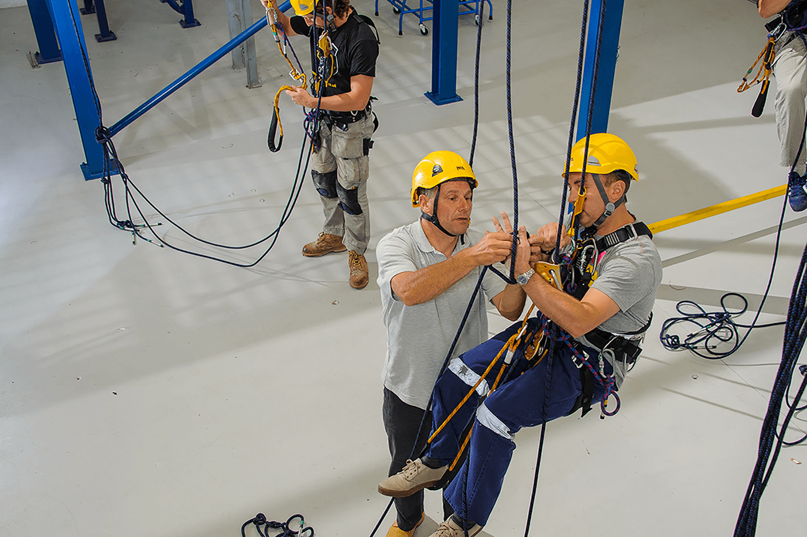 a man is showing another man dangling from a rope how to tie a knot correctly