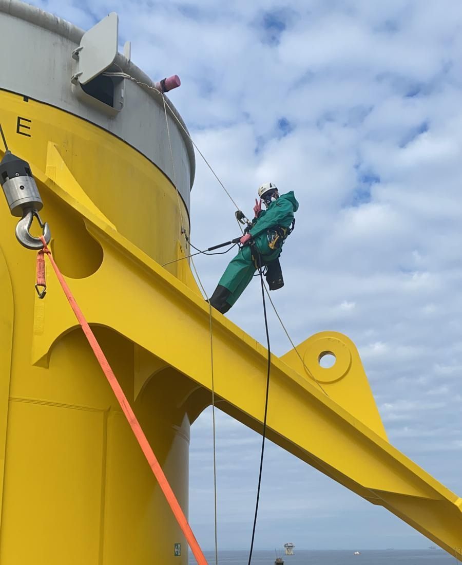 a man is dangling from a rope on a steep slope above water