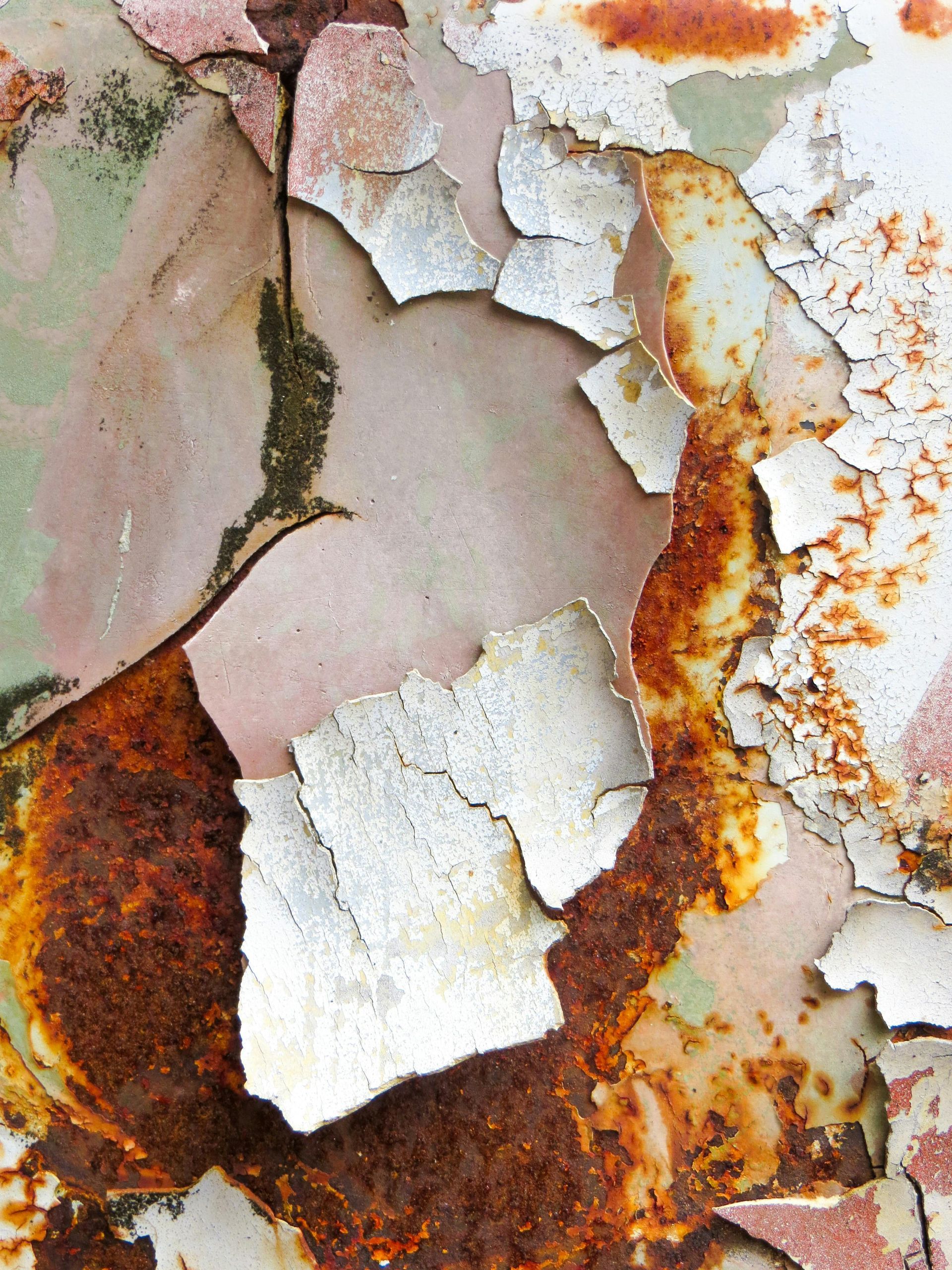 Cracked and peeling paint on rusted metal; shades of white, orange, and pale pink.