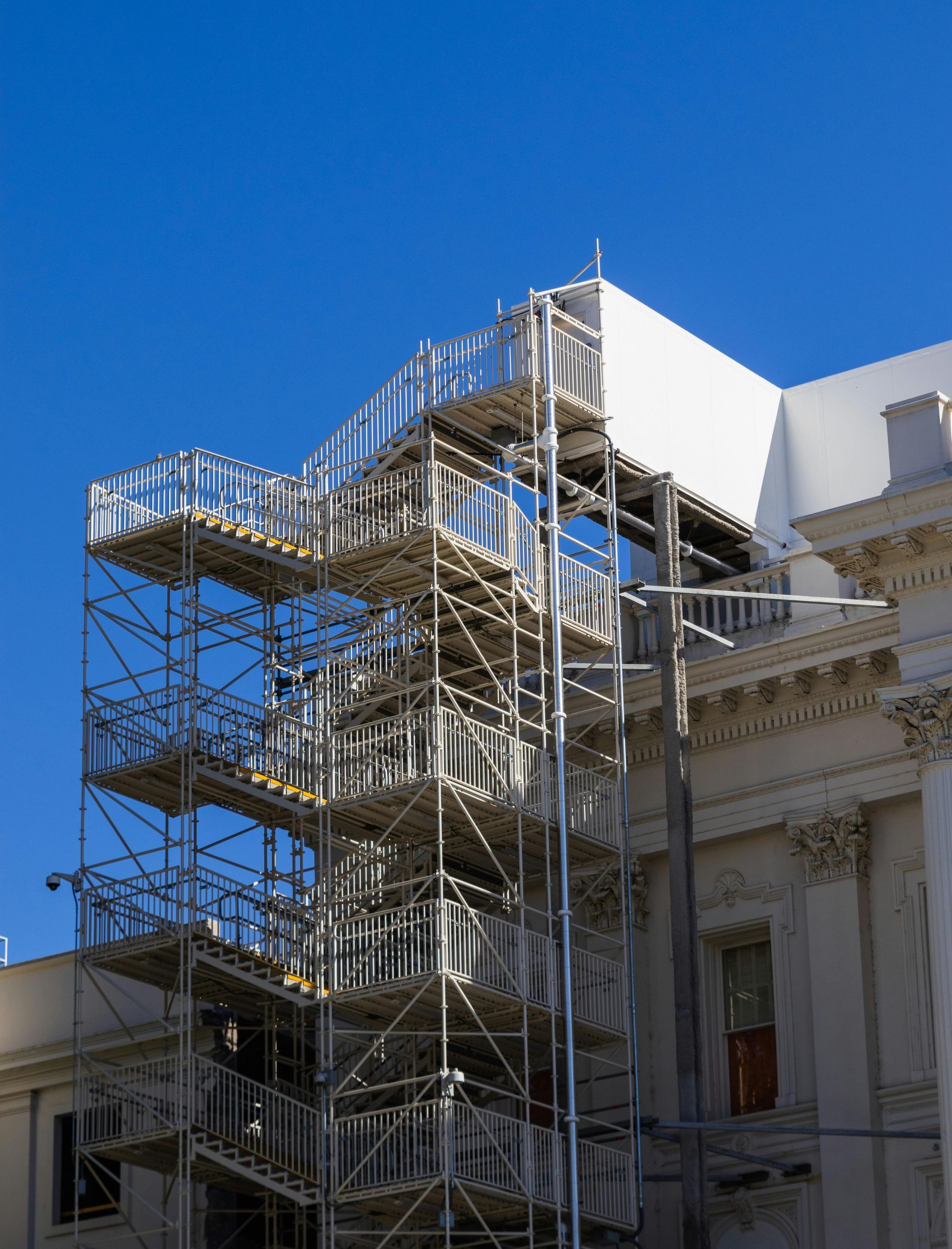 Scaffolding on the side of a building under a clear blue sky in Belfast.