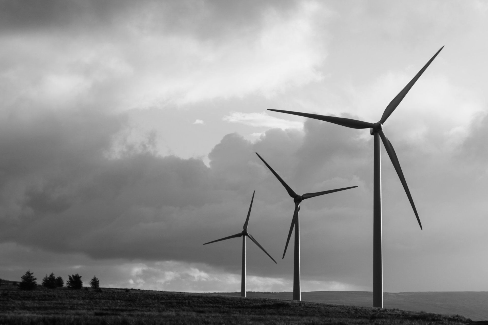 A black and white photo of three wind turbines on a hill