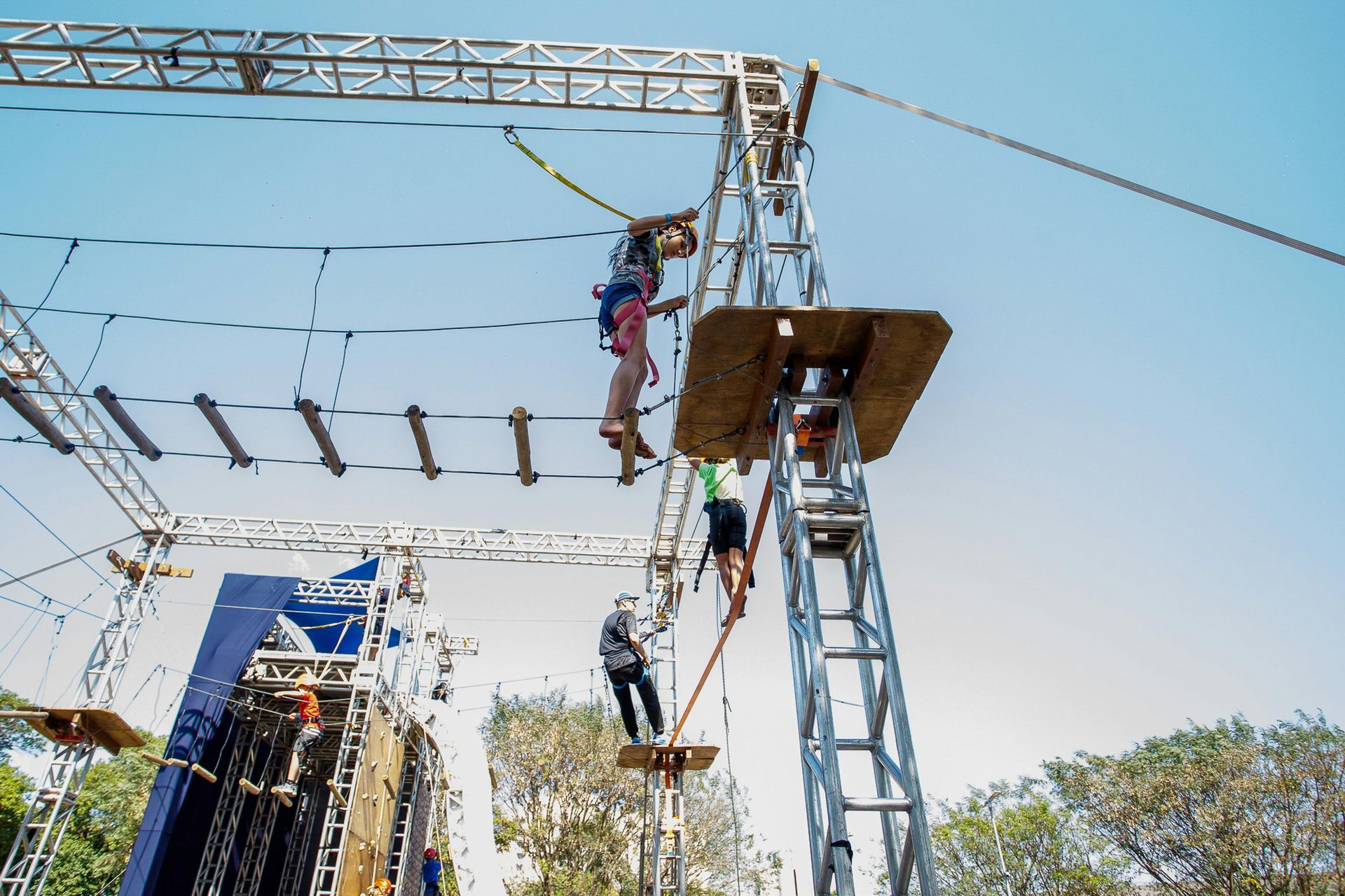 People navigating an outdoor high ropes course, walking across ropes and climbing ladders.