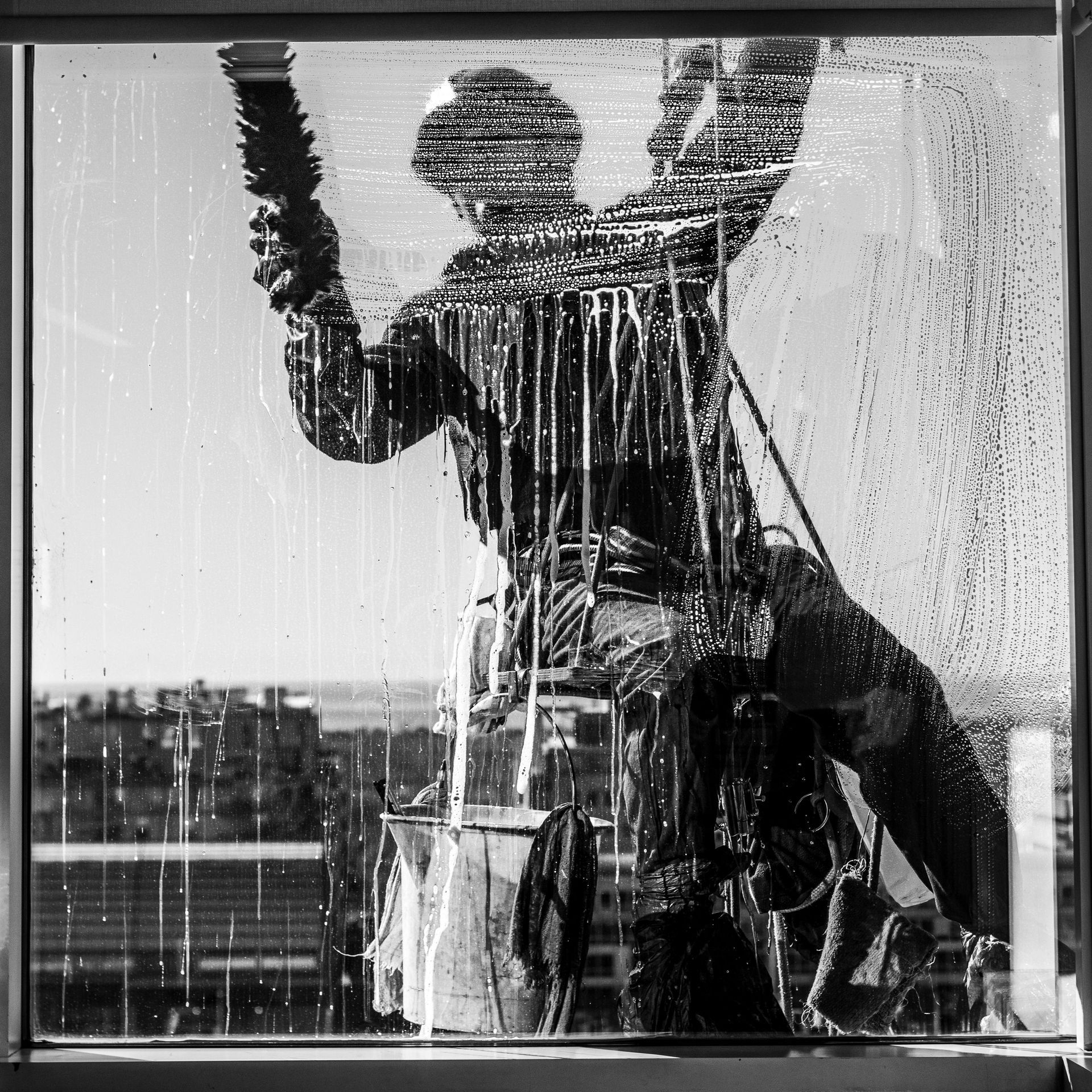 A black and white photo of a man cleaning a window
