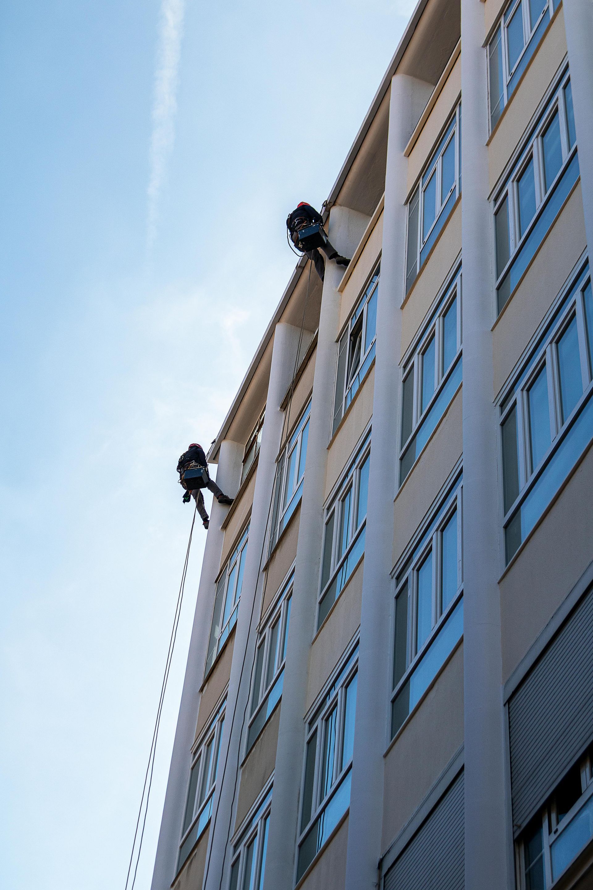 A man in a harness is climbing up the side of a building.
