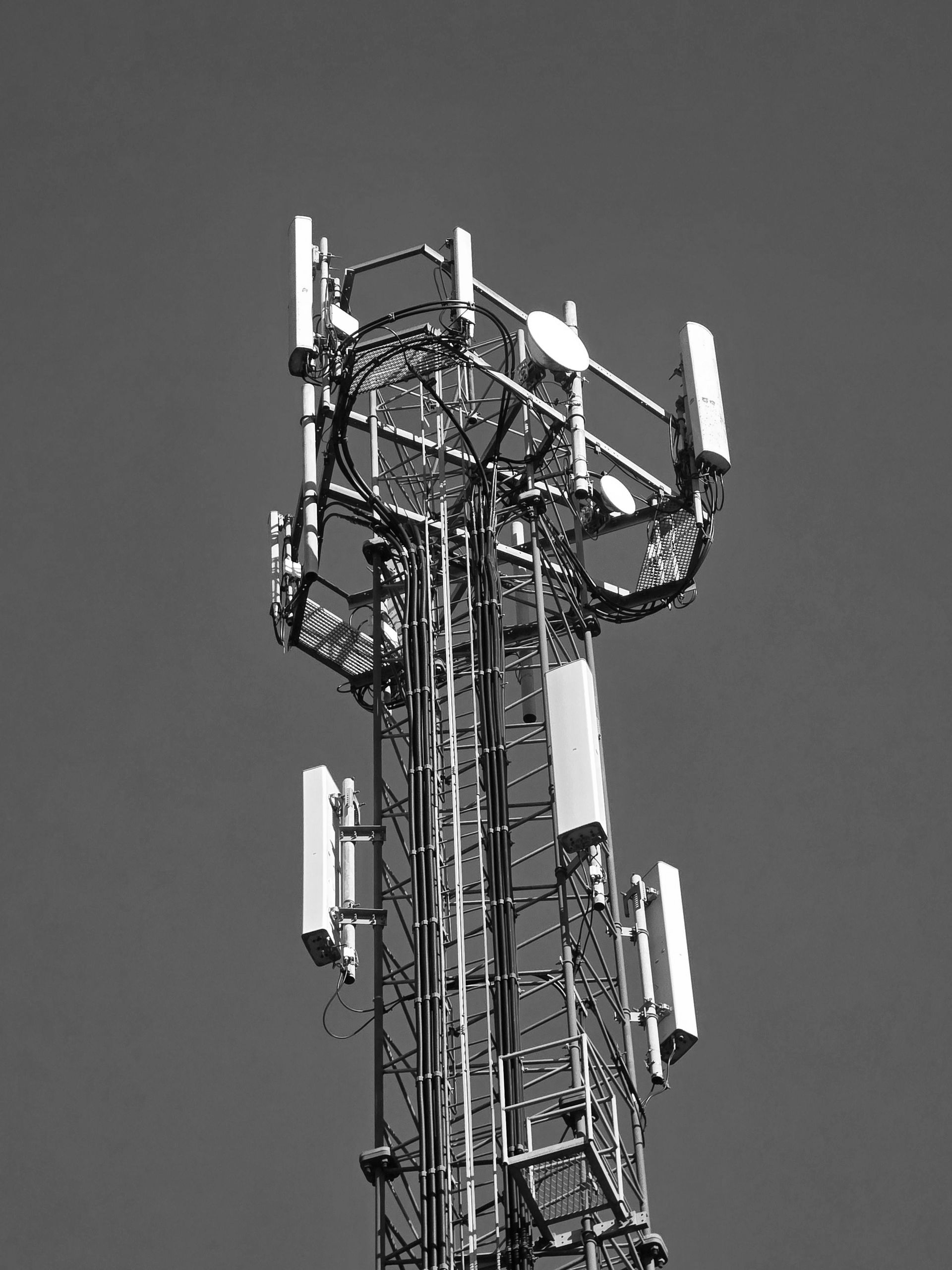 Cell tower with multiple antennas against a clear blue sky