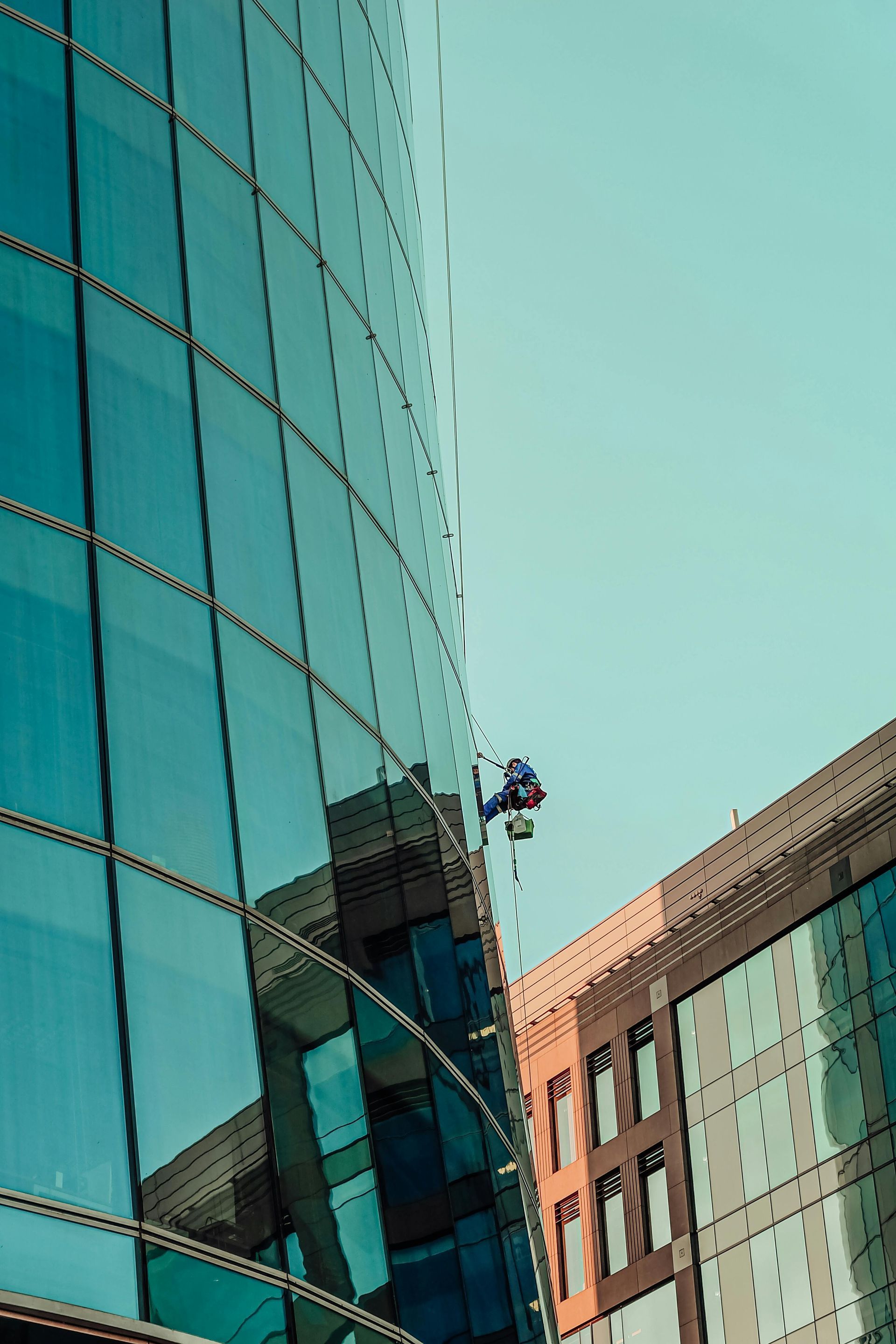 A man is climbing up the side of a tall building using ropes