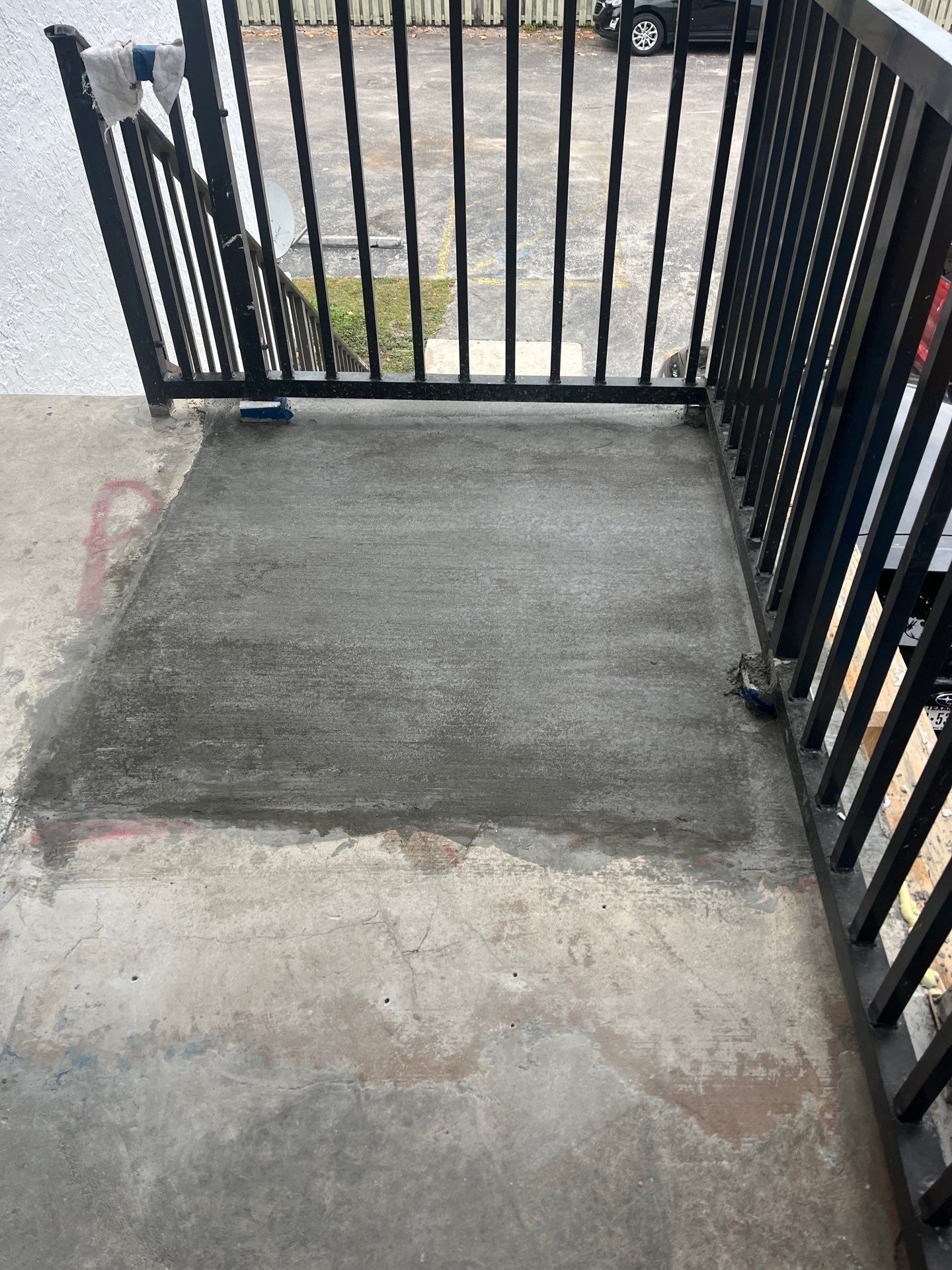 A concrete walkway leading to a balcony with a metal railing.