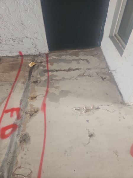 A concrete floor with a door and a window in the background.