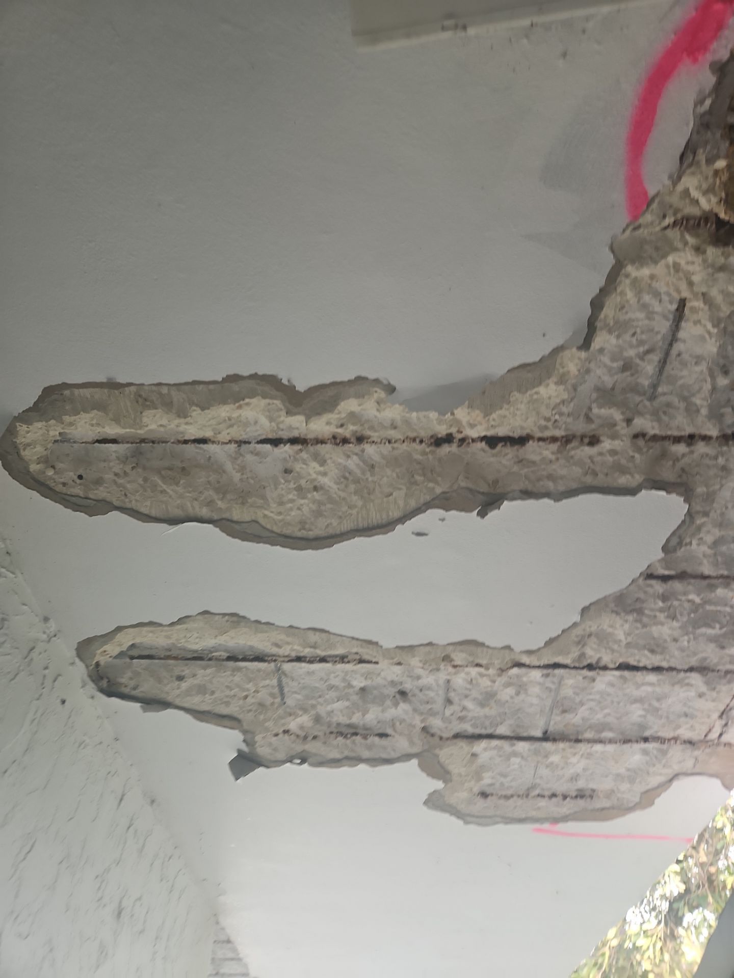 A concrete wall with a lot of holes in it is sitting on top of a concrete floor.