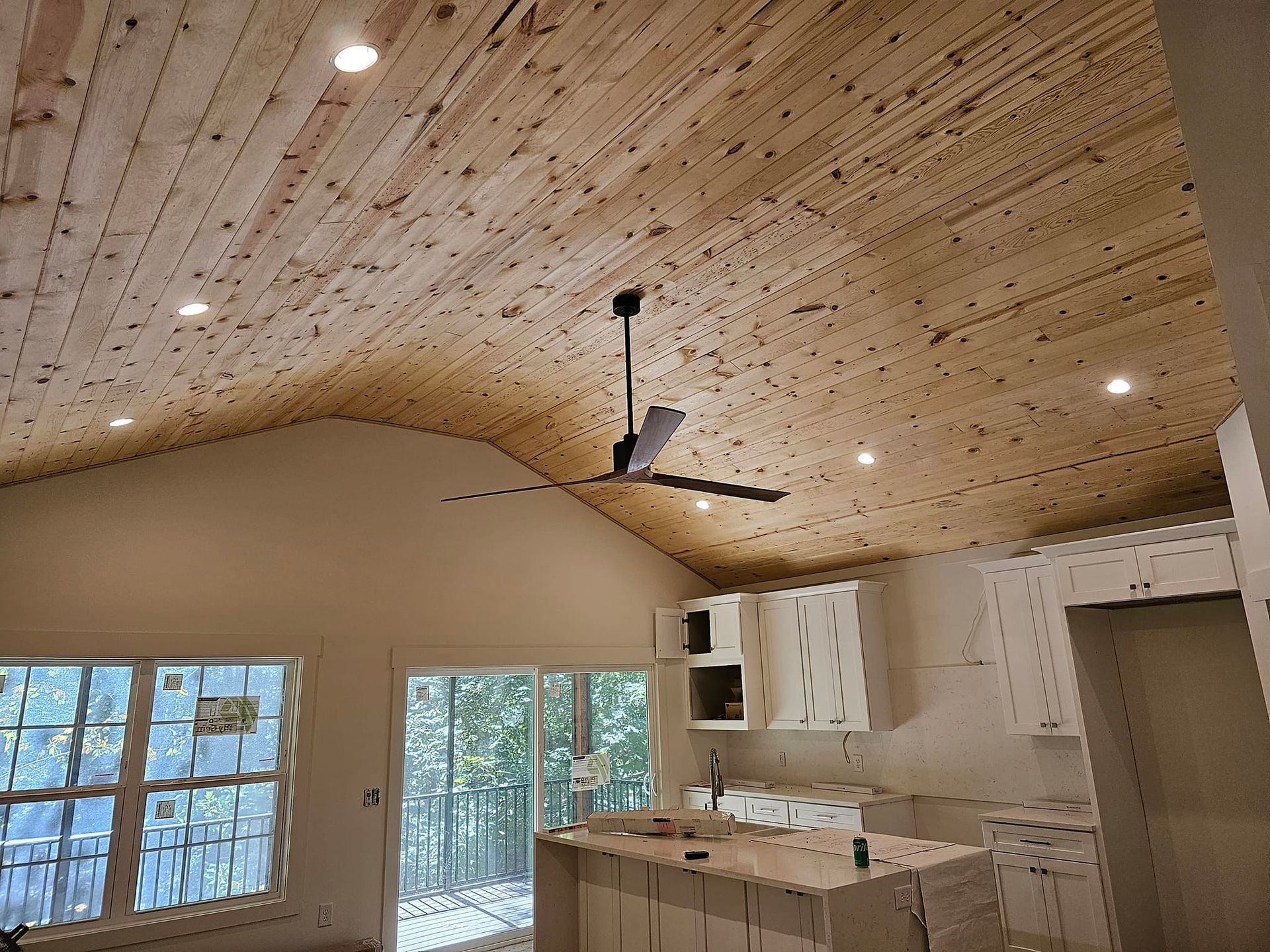 Interior view: kitchen with wooden ceiling, recessed lights, ceiling fan, and white cabinets.