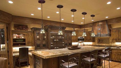 Rustic kitchen with wooden cabinets, island, and pendant lights.